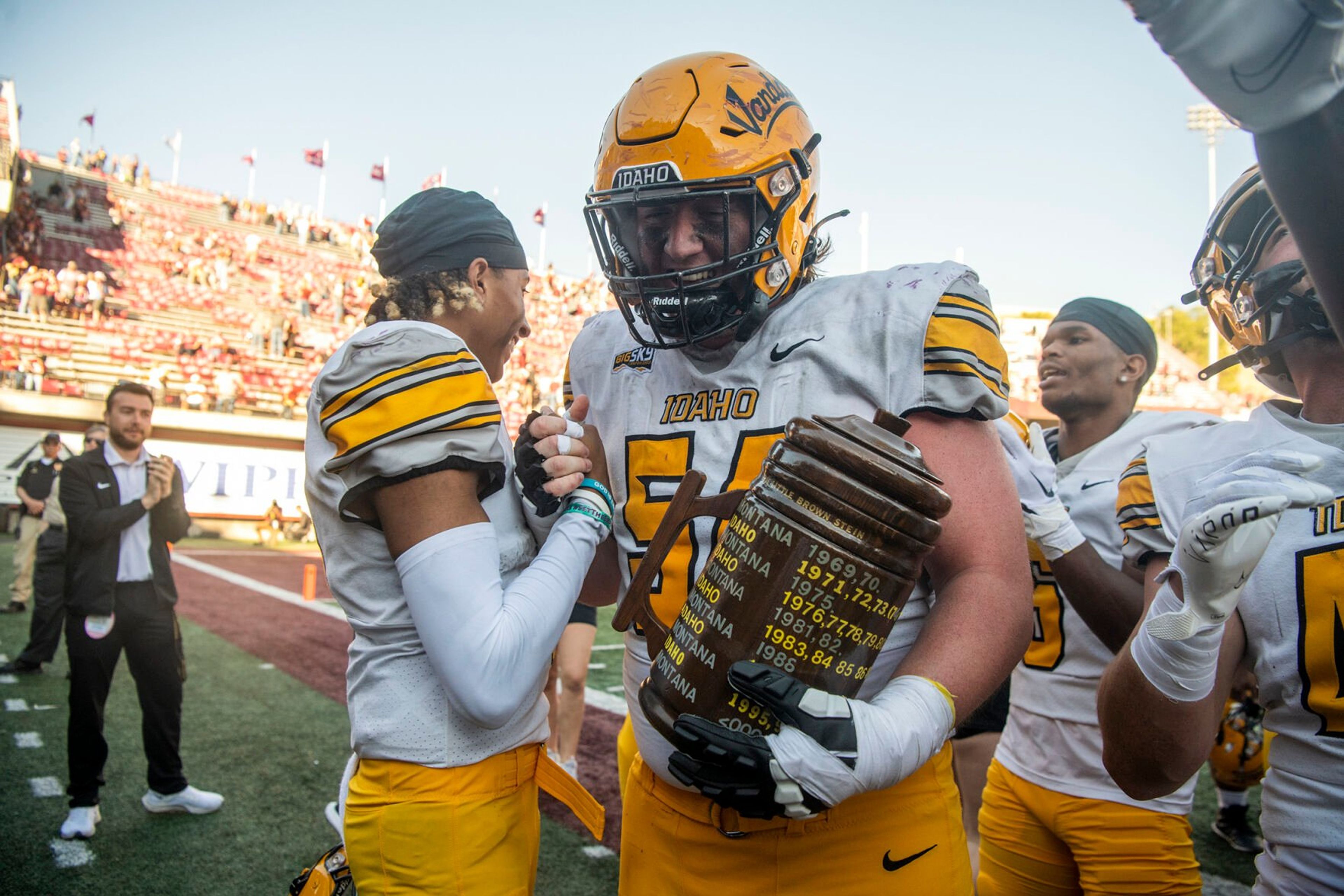 Idaho quarterback Gevani McCoy, left, and defensive lineman Ben Bertram celebrate with the Little Brown Stein after the Vandals upset second-ranked Montana in a Big Sky game Saturday at Washington-Grizzly Stadium in Missoula, Mont.