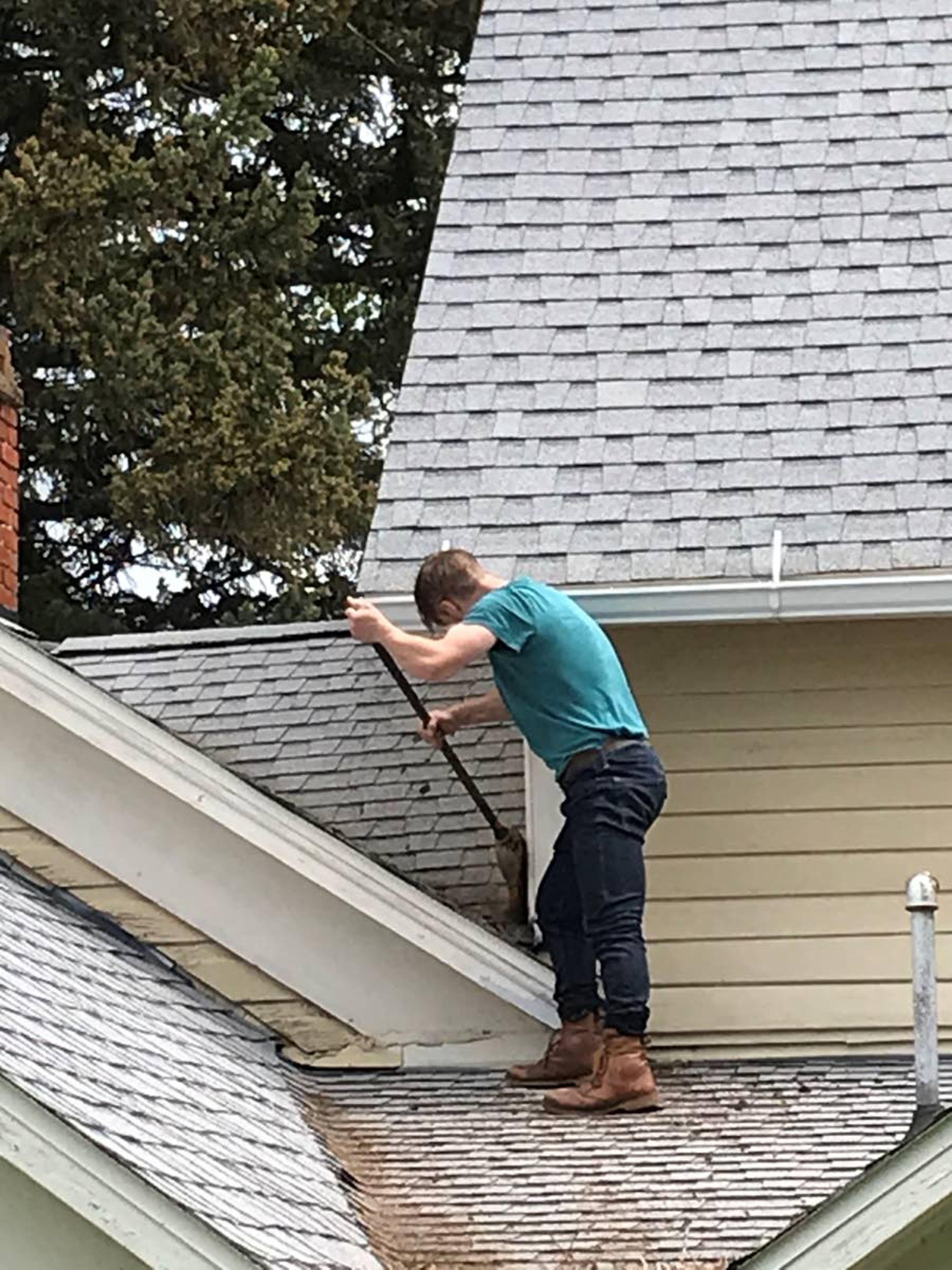 Nathan Lorang uses a broom to clean a roof Saturday at White Spring Ranch outside Genesee. Lorang family members and other volunteers complete maintenance and restoration projects every Memorial Day Weekend. John and Mary Lorang bought the property, which is now a museum and archive library, in the 1880s.