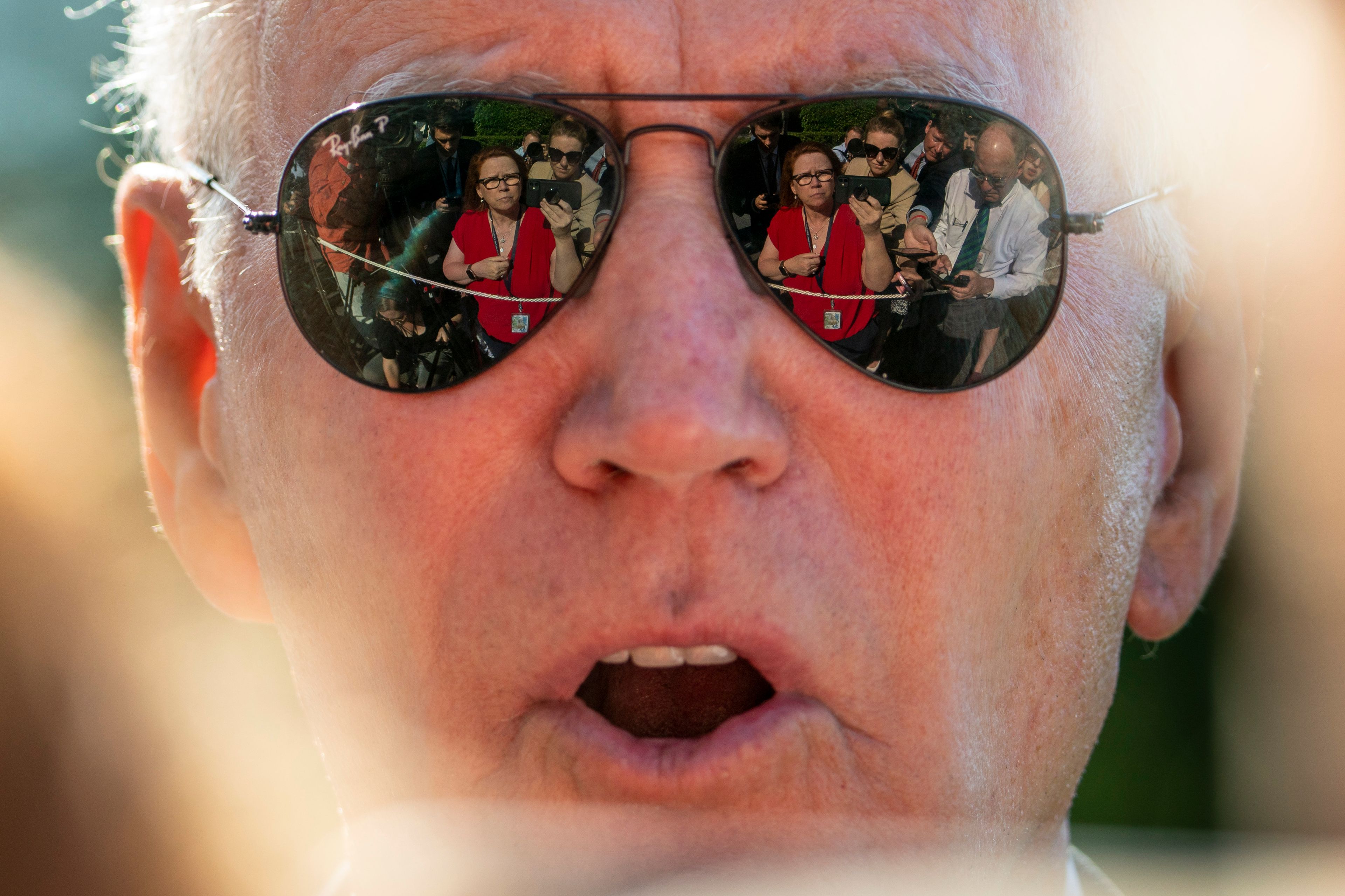 NBC Senior White House Correspondent Kelly O'Donnell, Reuters White House Reporter Steve Holland, right, and other members of the media are visible in the sunglasses of President Joe Biden as he speaks on the South Lawn of the White House in Washington, Monday, May 30, 2022, after returning from Wilmington, Del. (AP Photo/Andrew Harnik)