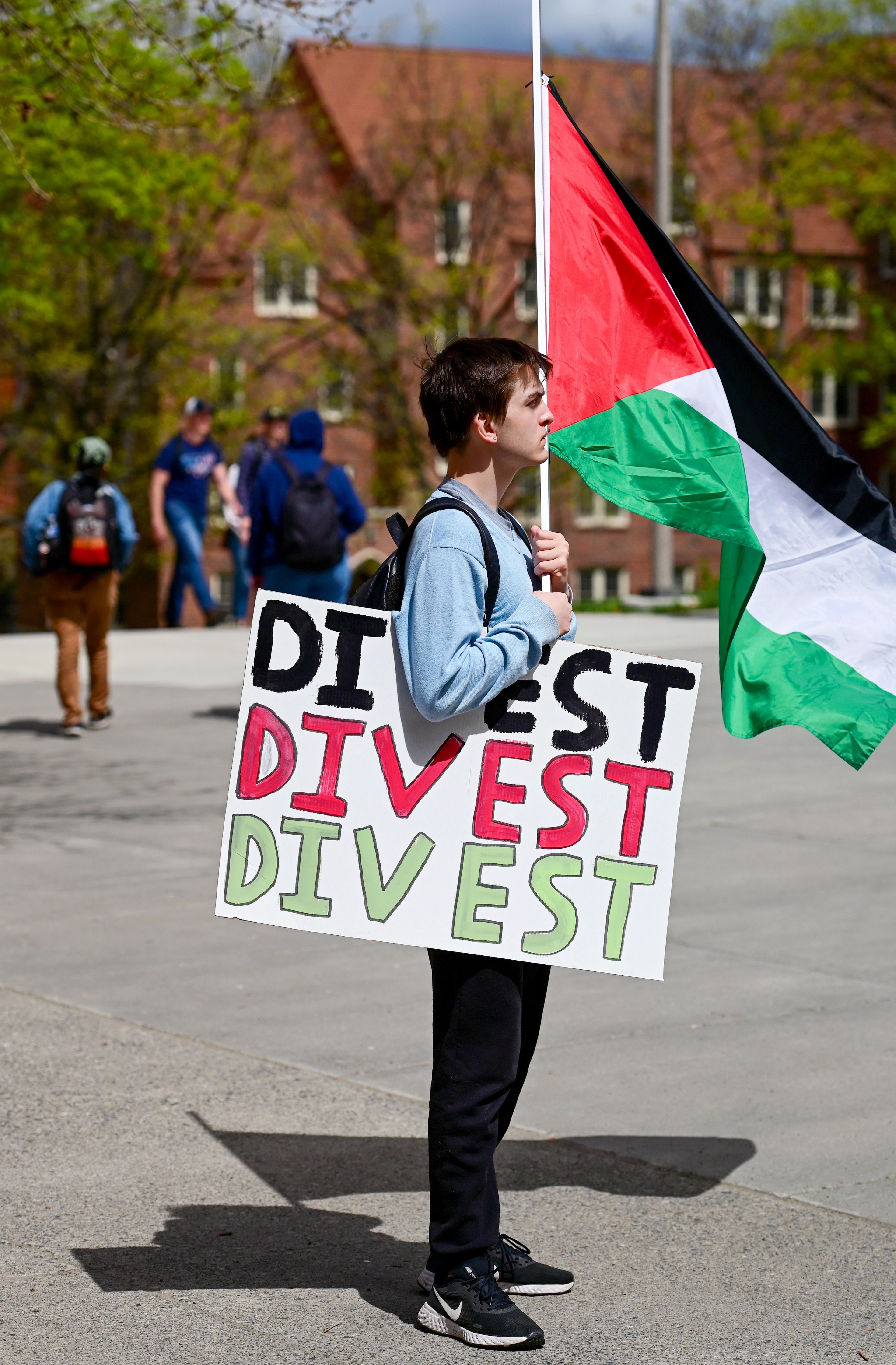 Connor Luce, a Washington State University student who helped organize a pro-Palestine protest at WSU on Wednesday, holds a flag and poster while taking part in the Palestine Week of Action demonstration at the University of Idaho in Moscow on Thursday.