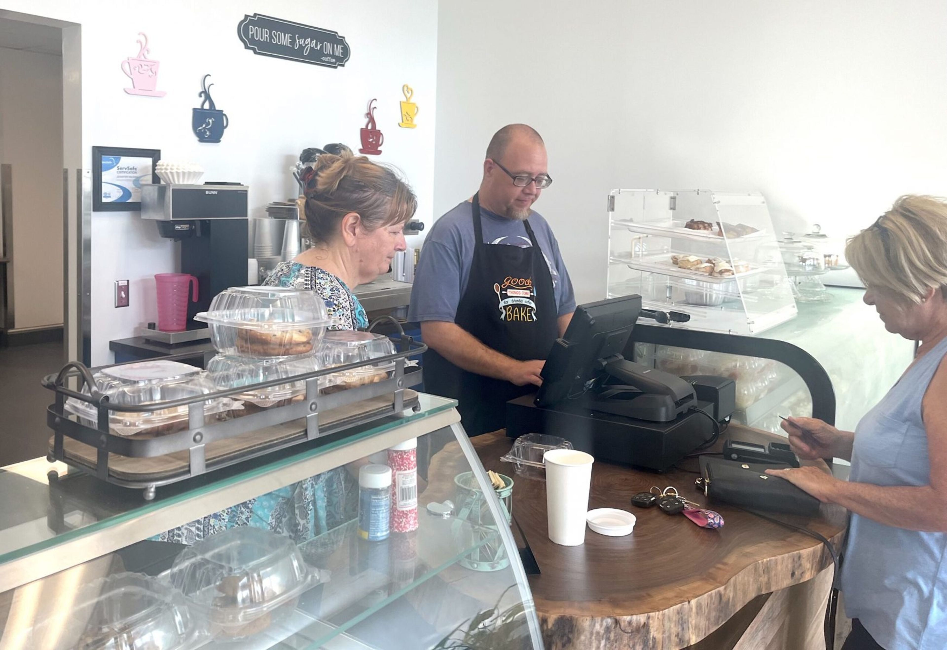 Essential Edibles co-owner Jennifer Scott Wilkins and head baker Mike Gordon serve a customer on Aug. 15, the bakery’s first day of business. Hannah Whitley Camarena | Enterprise