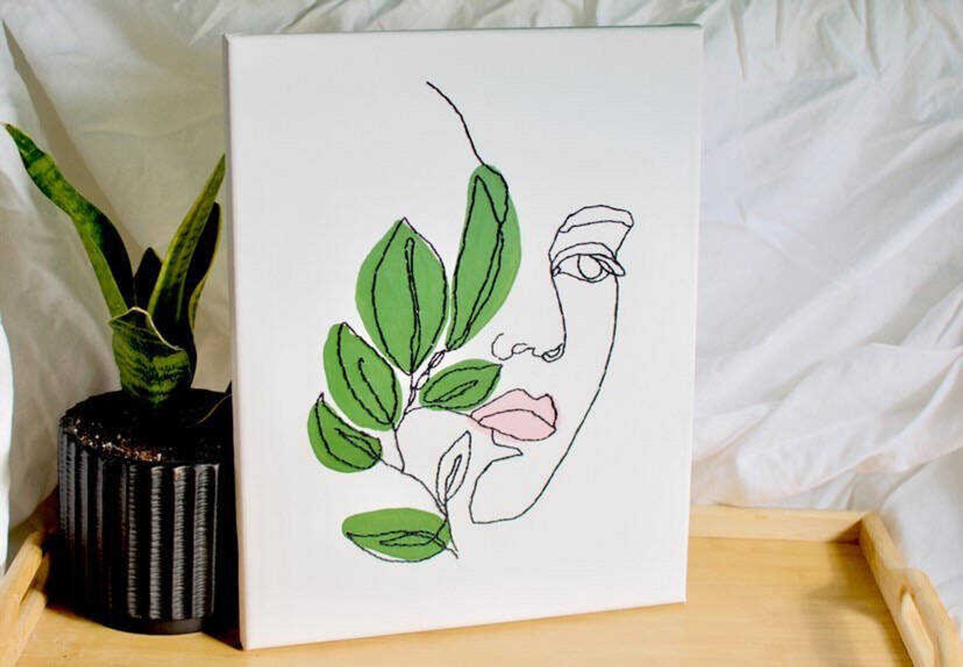 One of Kaleigh Oliver’s embroidered canvas paintings is pictured in a product shot. Almost all of Oliver’s paintings depict outlines of anonymous women because she believes women are “awesome and empowering.” 