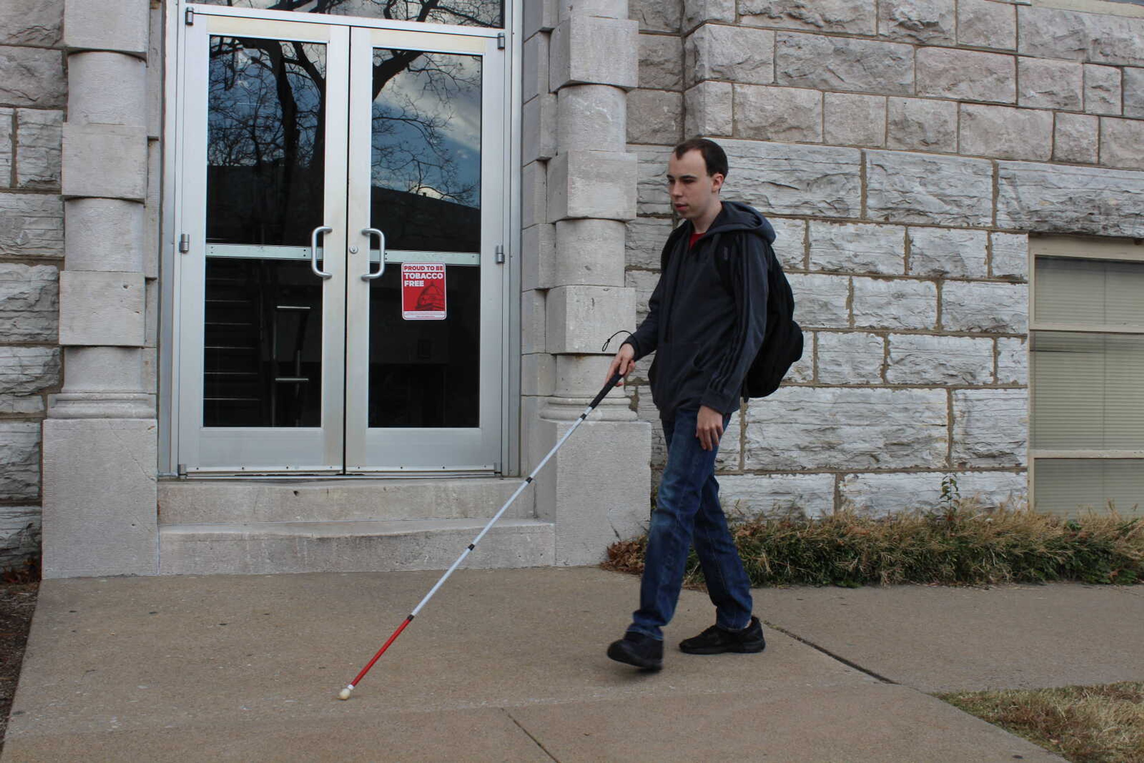 Brandon Hahs uses familiar routes and a walking cane to make his way around campus.