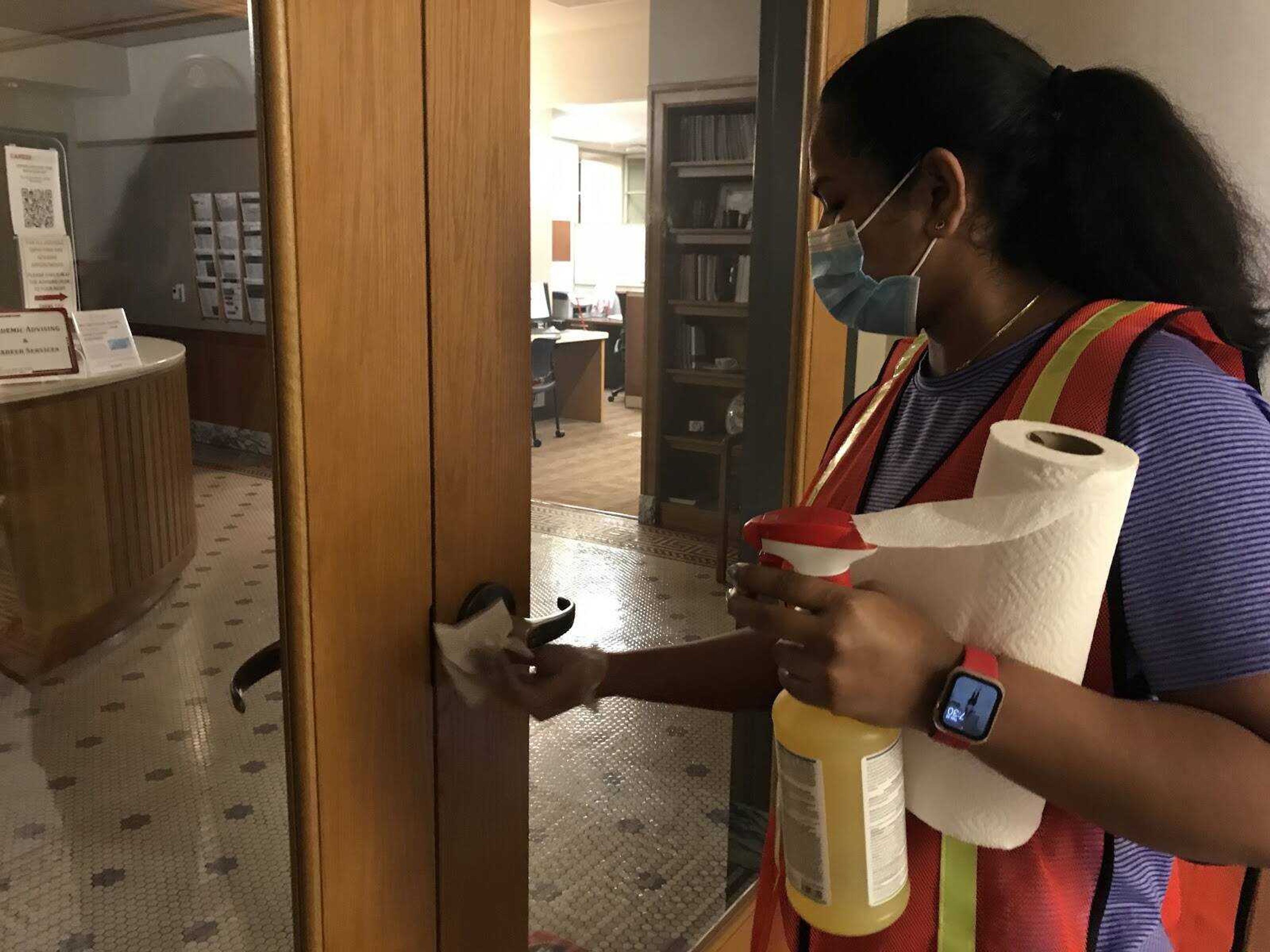 Computer science major Aruna Kamma disinfects the entryway to the Registrar’s office in Academic Hall.