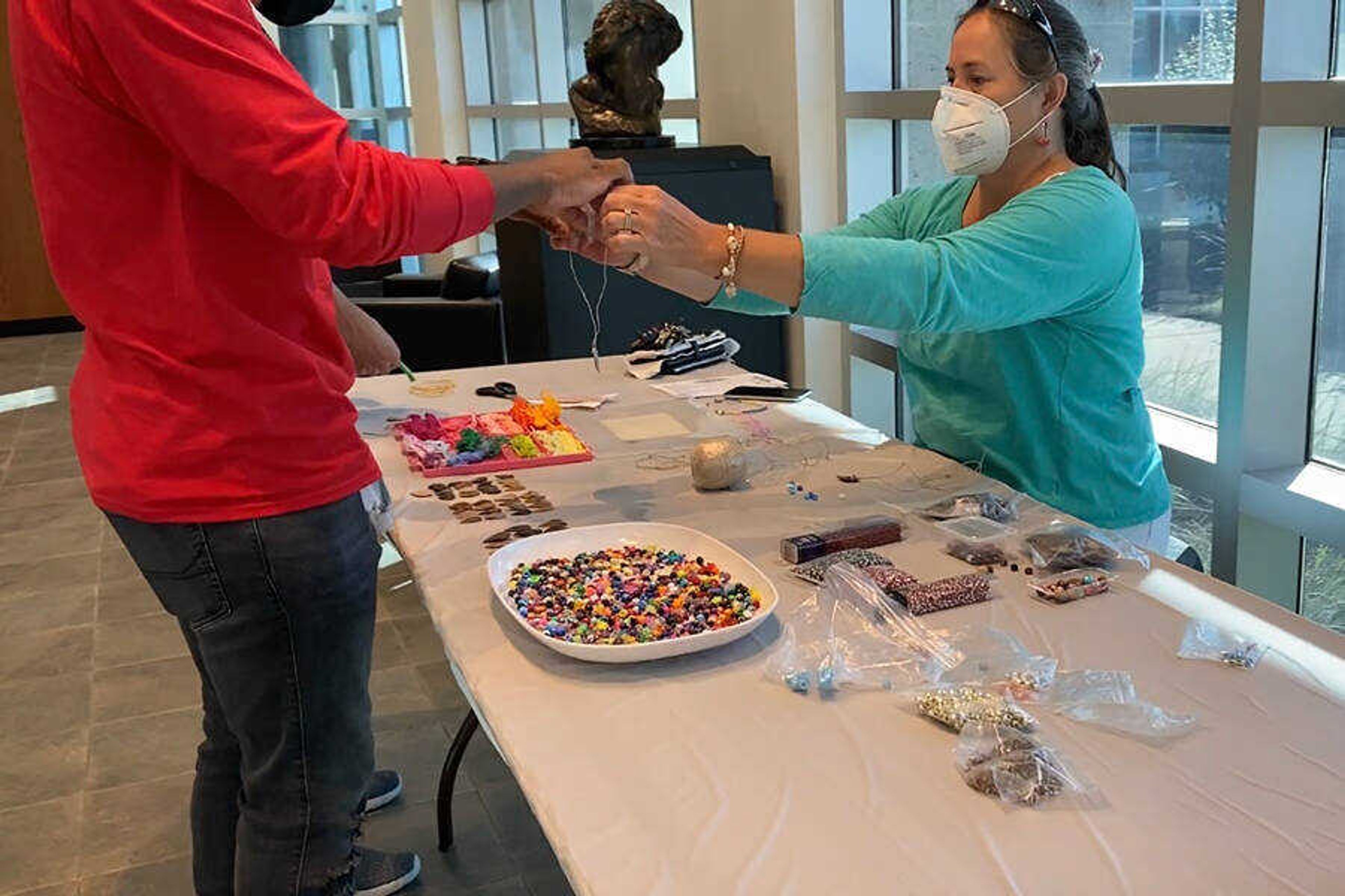 Museum Curator Ellen Flentge assisted freshman Tyrell Gilwater with his arrowhead necklace at the Make-and-Take event held on Sept. 4 at Crisp Museum.