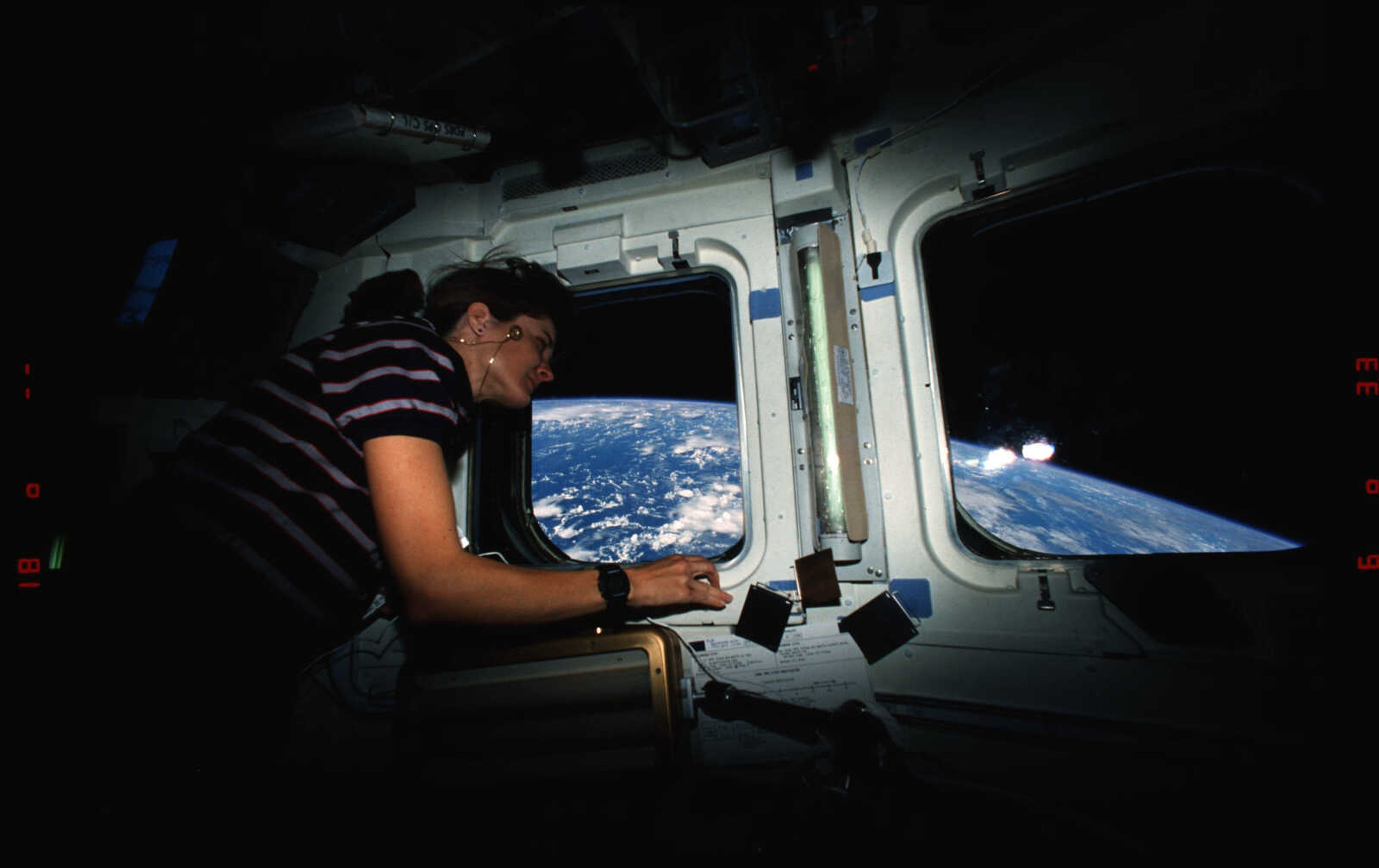 Linda Godwin looks through window on flight deck while on space flight STS-37, the eighth flight of the Space Shuttle Atlantis.