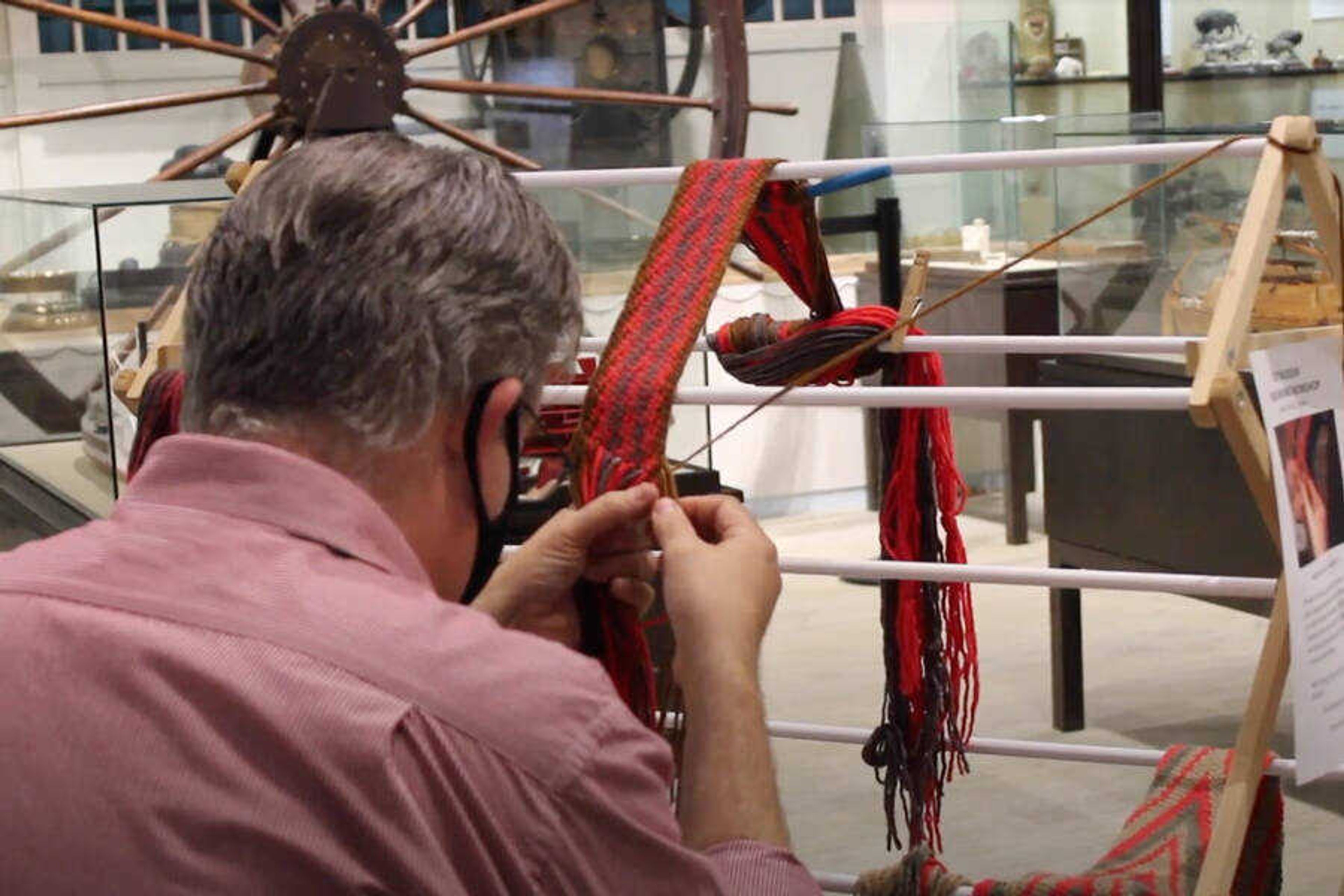 Crisp Museum Manager Jim Phillips weaves fabric in a demonstration, as a part of the Night at the Museum event held on Aug. 29.