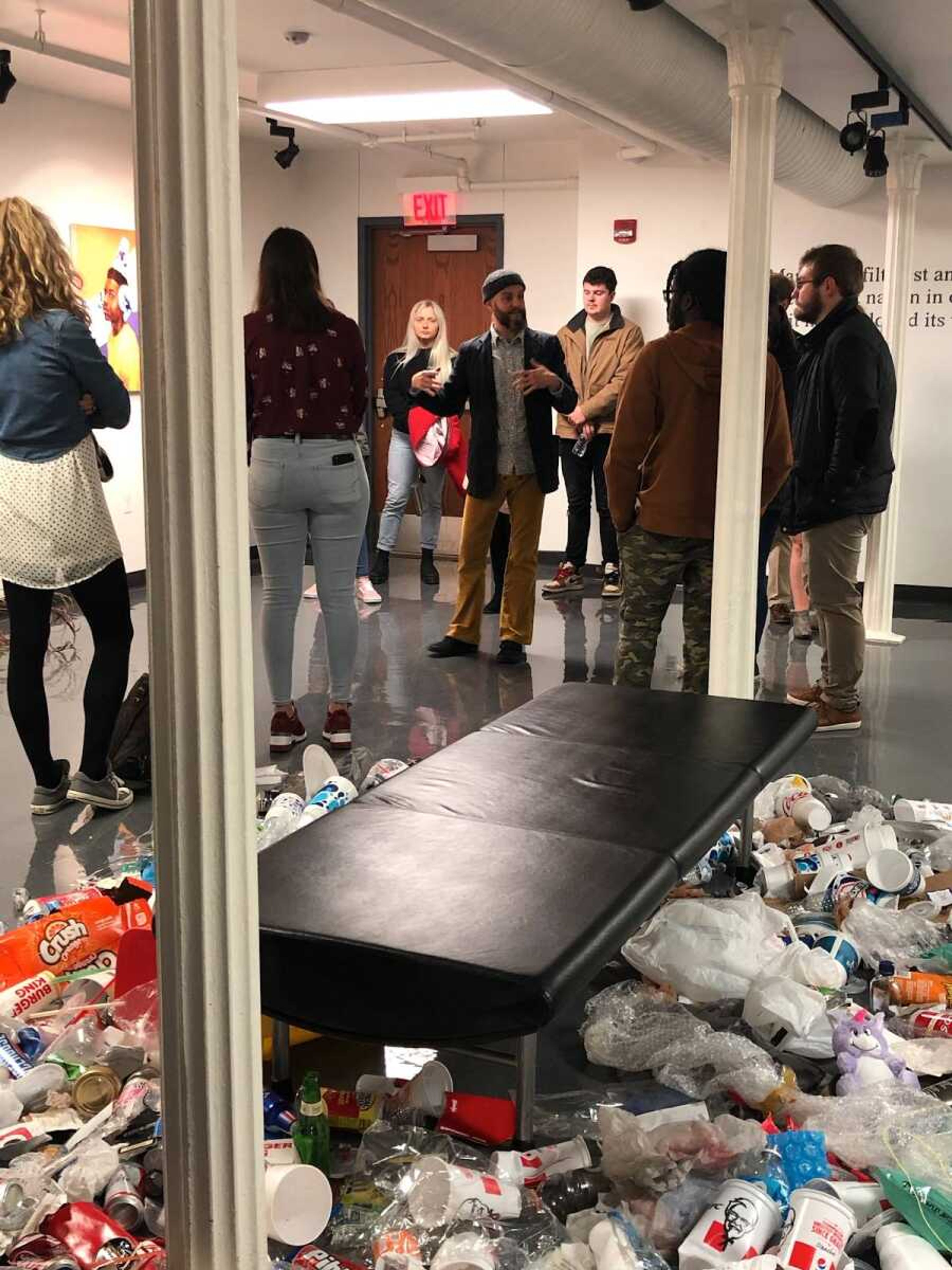 Artist, Jousha Newth, explains his newest exhibit “Acts of Unreason” with “Garbage Patch People” art piece surrounding the viewers. 