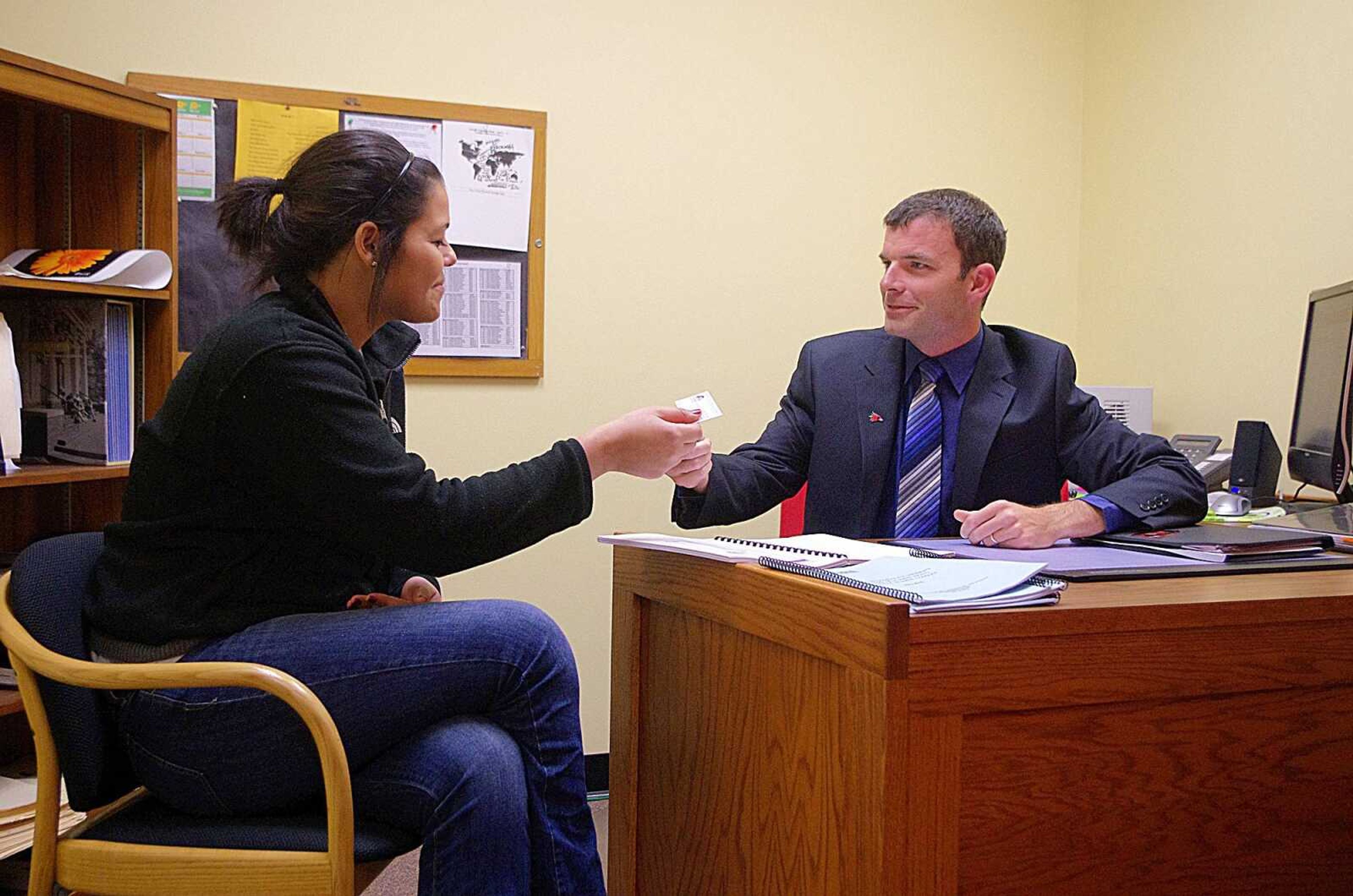 Graduate assistant Kasey Fraser-Smith, left, receives a business card from Jeremy McBroom on Monday in his office, so she can contact him if she comes up with any questions. Photo by Nathan Hamilton