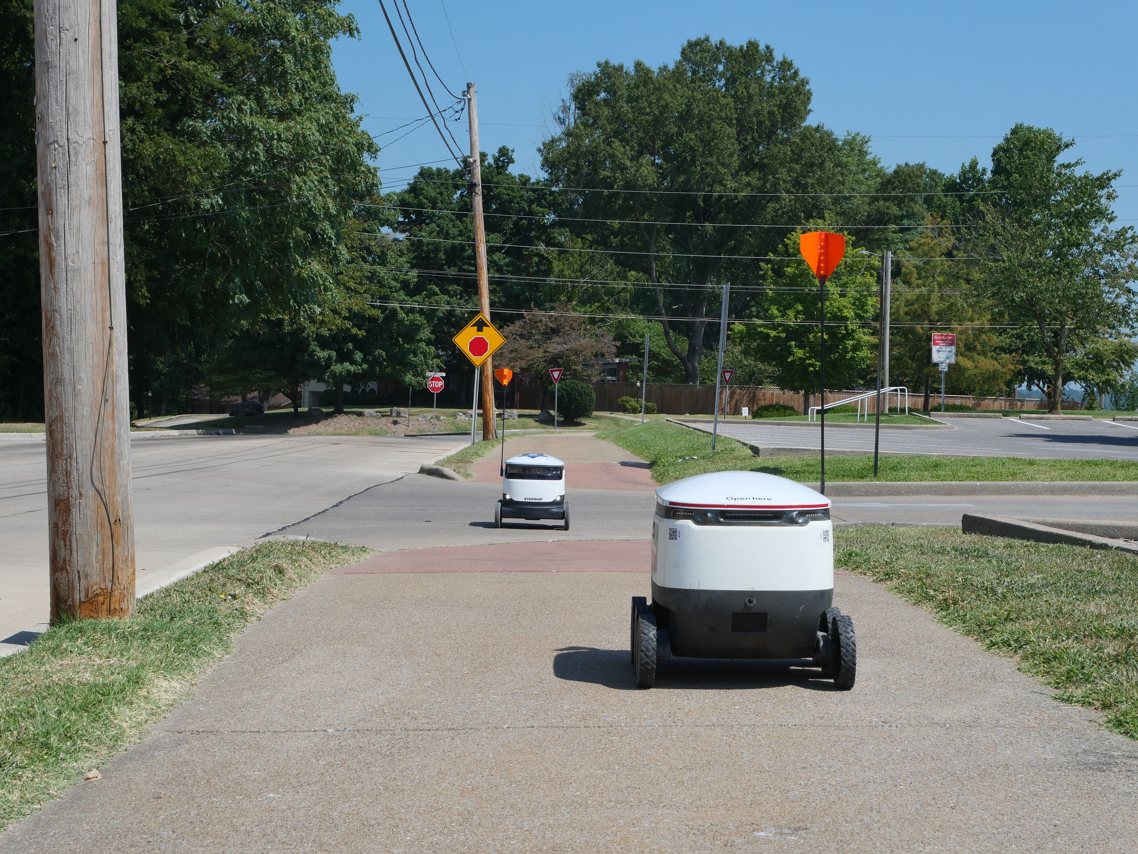 Two Starship delivery robots pass each other outside of Dempster Hall.