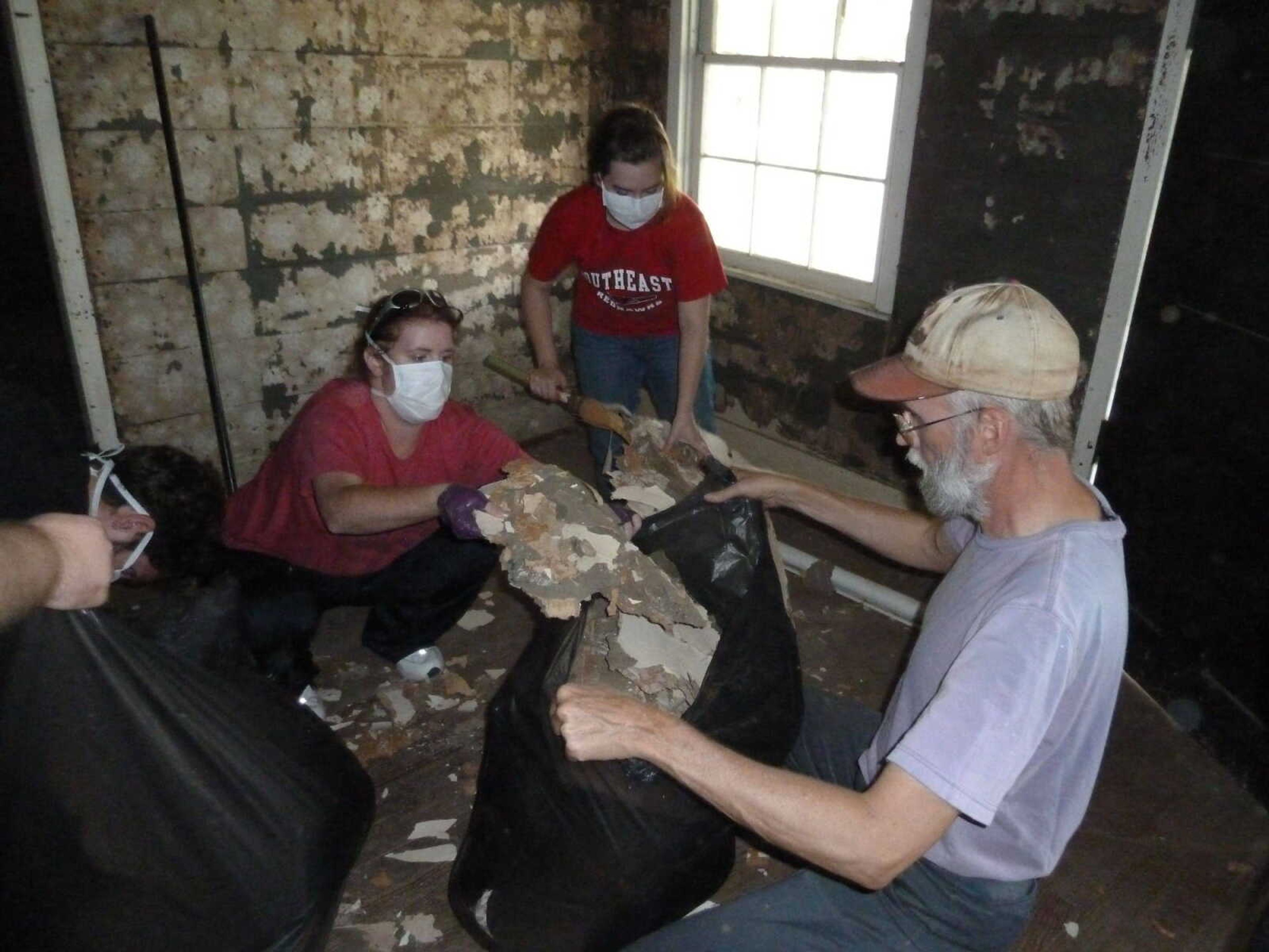 Historic preservation students remove damaged wallpaper at the Miller House. - Submitted photo