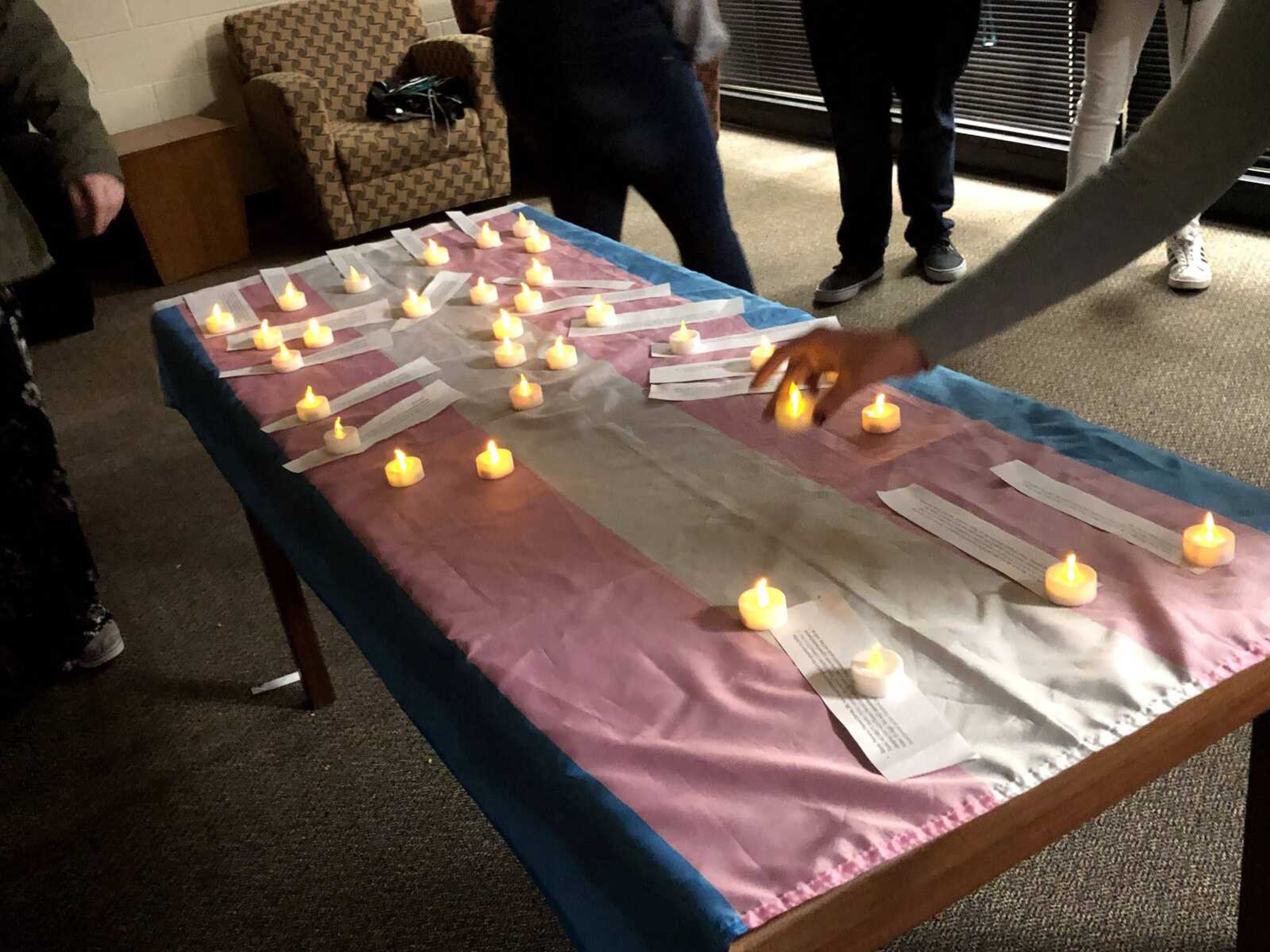 Attendees place candles on top of the transgender flag at the candle lit vigil on Nov. 29 in remembrance of those who were murdered due to their gender identity.