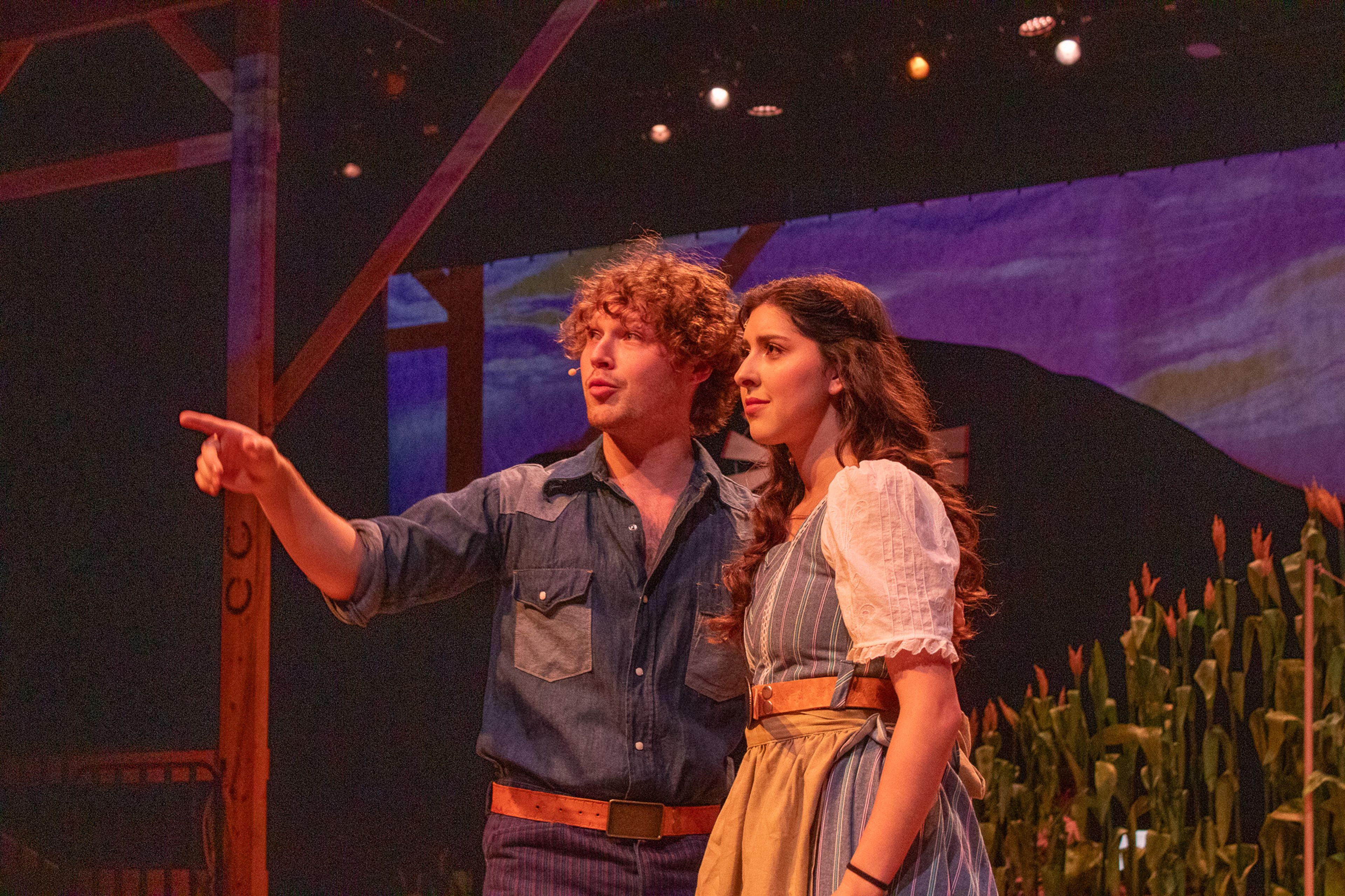 Curly, played by Garrett Langley, tells Laurey, played by Elise Bowles, about the fancy wagon he'd take her in for the box social dance