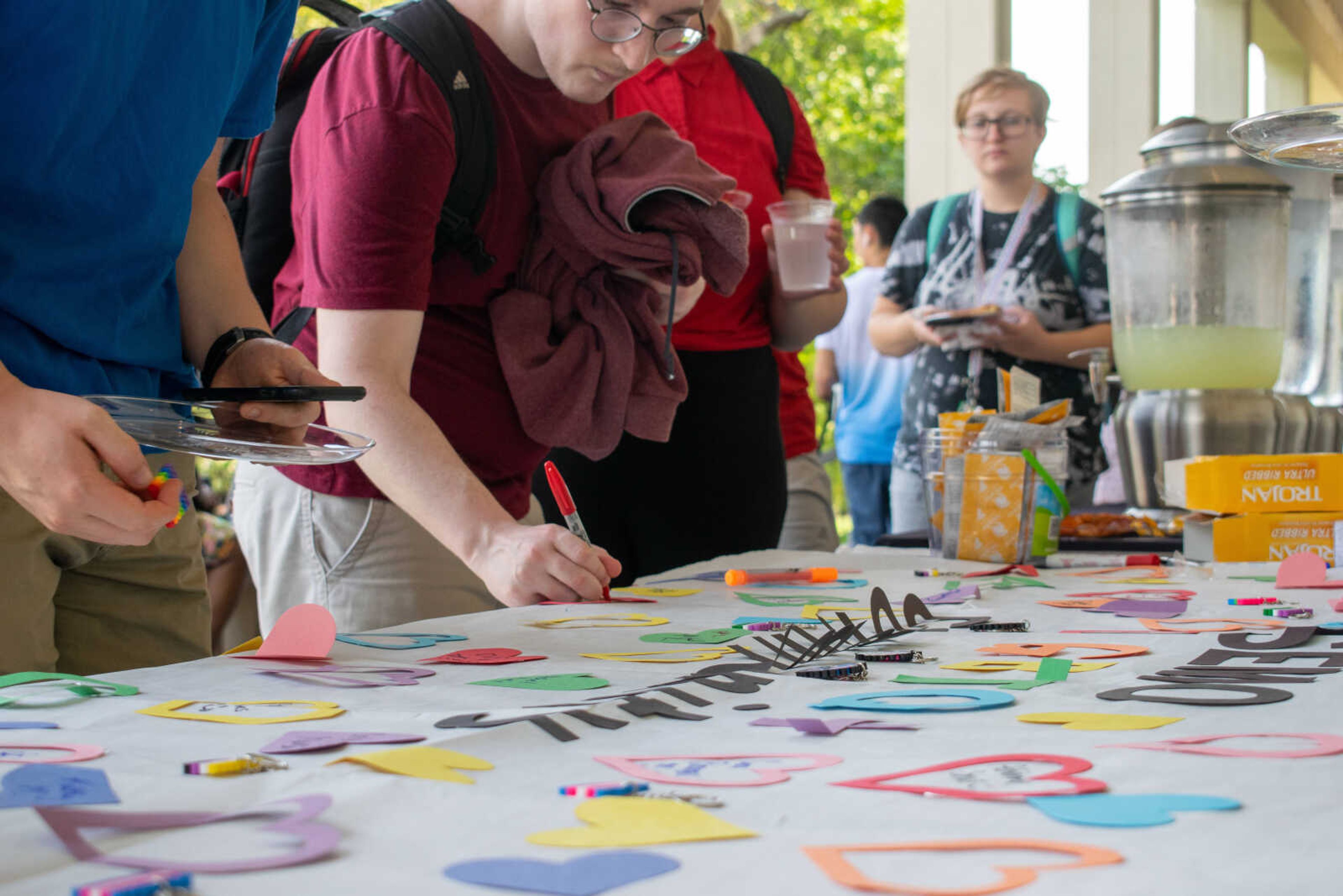 Picnic participants write down their names on the banner and taking a key chain provided by the organization outside of Kent Library on Wednesday, Aug. 21.