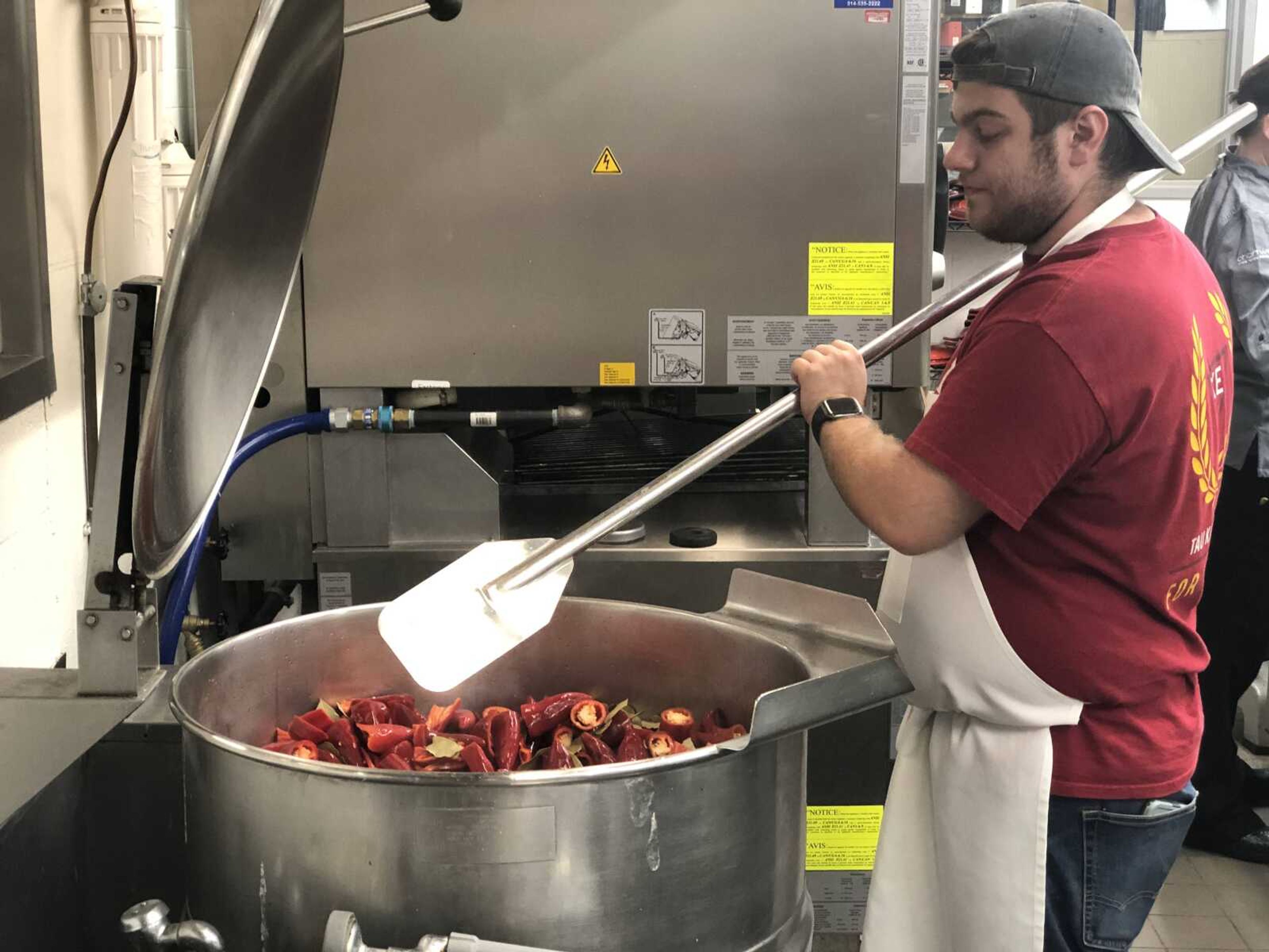 Senior Dennis Settles stirring all the ingredients for Hawk Sauce in a large pot in Chartwell's kitchen on Tuesday, Oct. 1.