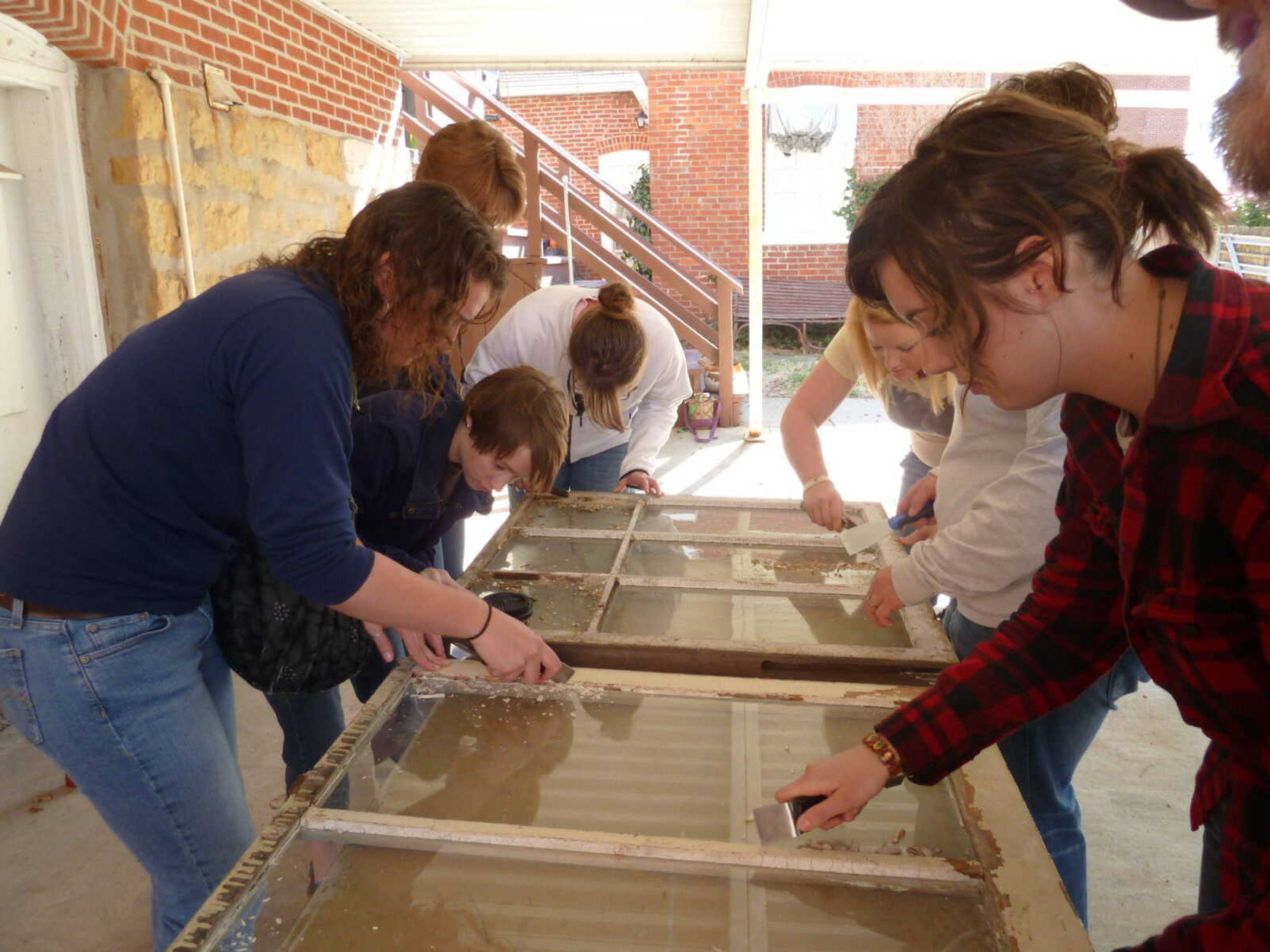 Historic preservation students learn how to remove and replace old window panes in the Historic Window Workshop. - Submitted photo