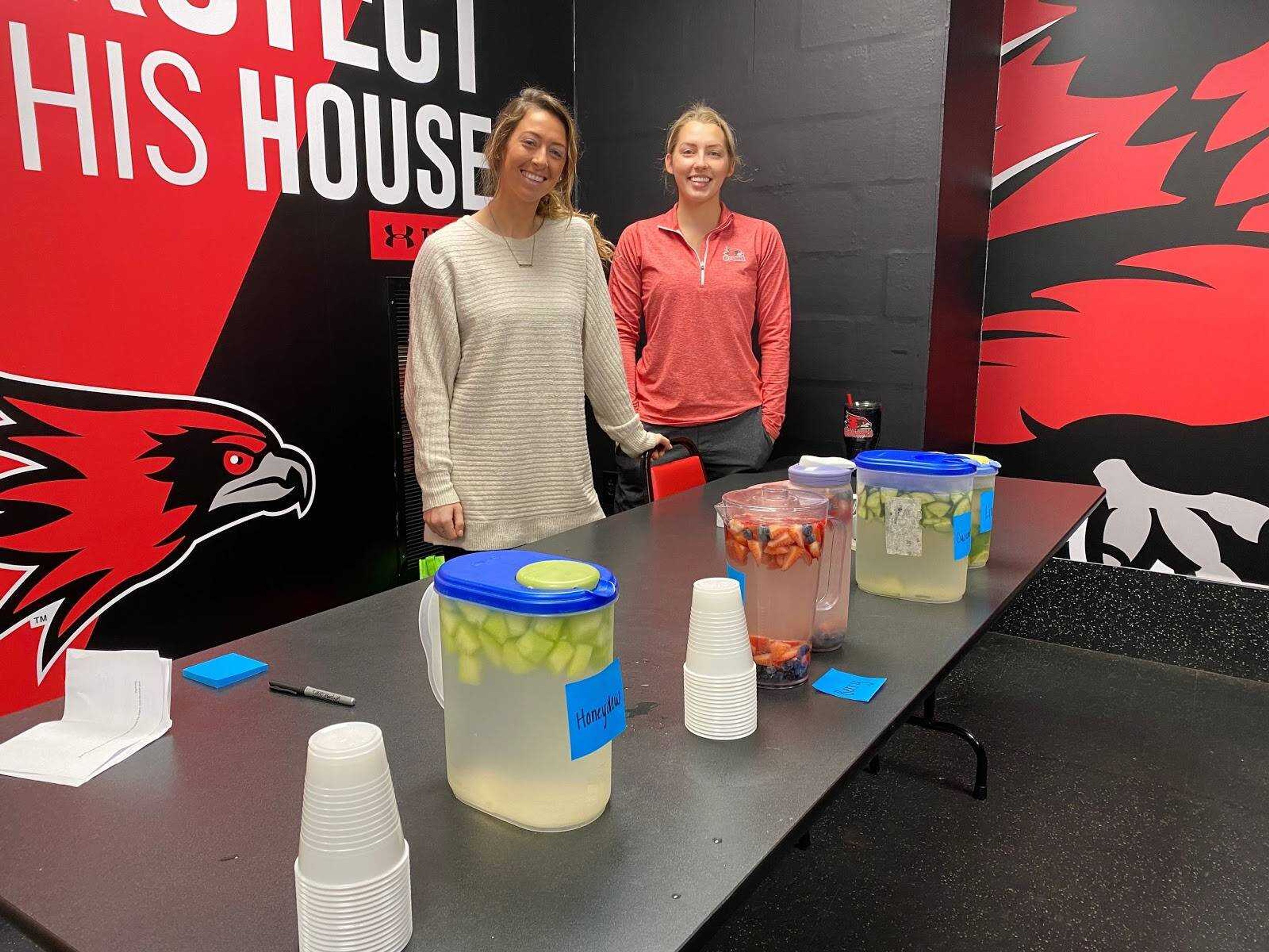 Parker Bandy (left) and Madeline Grimm (right) present different types of water to the softball team on Dec. 5 at the Holcomb Success Center.