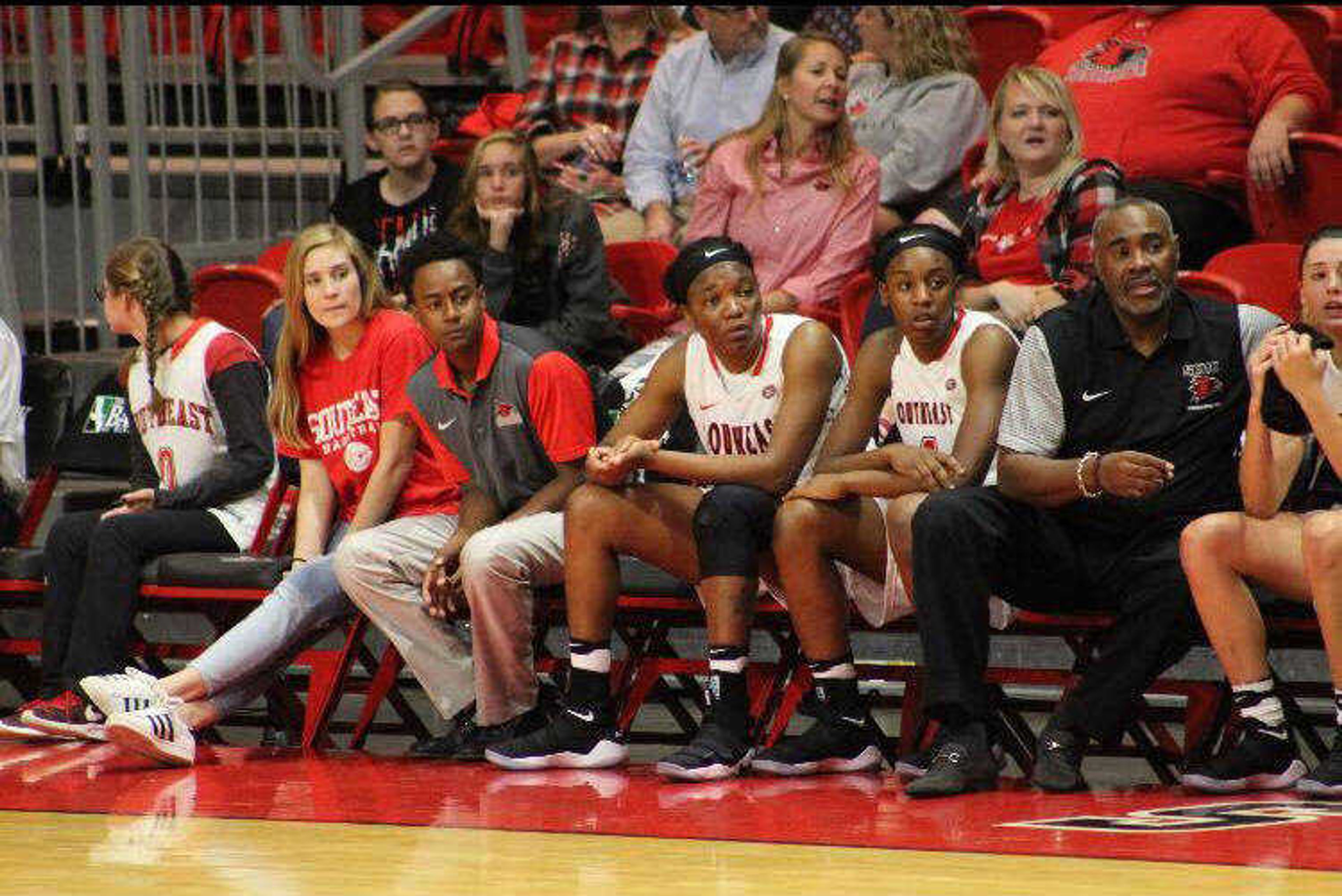 Student managers Bryan Doze and Dexter sit at the end of the bench during a women’s basketball game.

