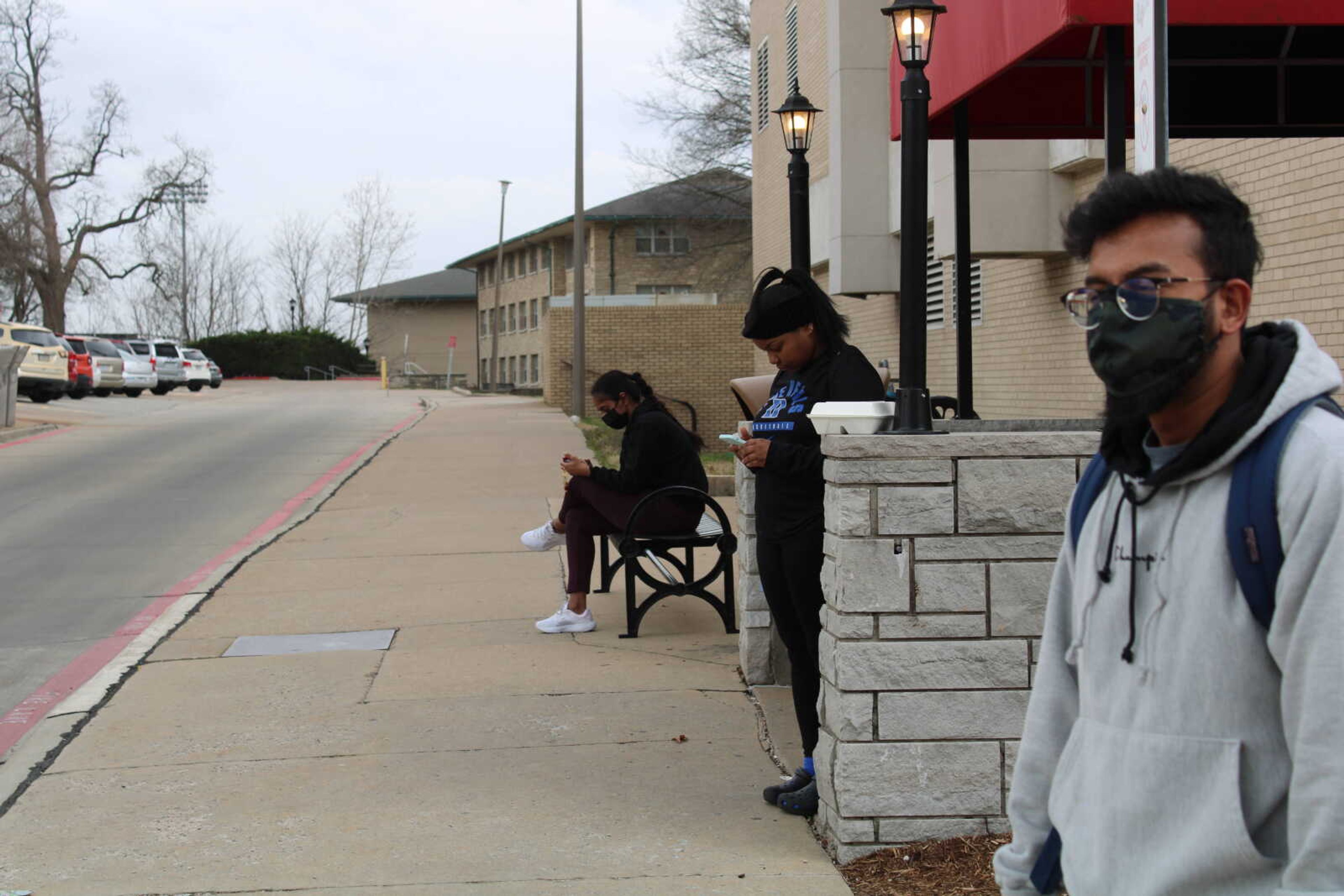 Ahmed Salehin waits outside the Starbucks on campus with two other students. He said he will often do homework there because it is the best place to see the bus. But with a tracking app, he said he would have more freedom to work out or go somewhere else.
