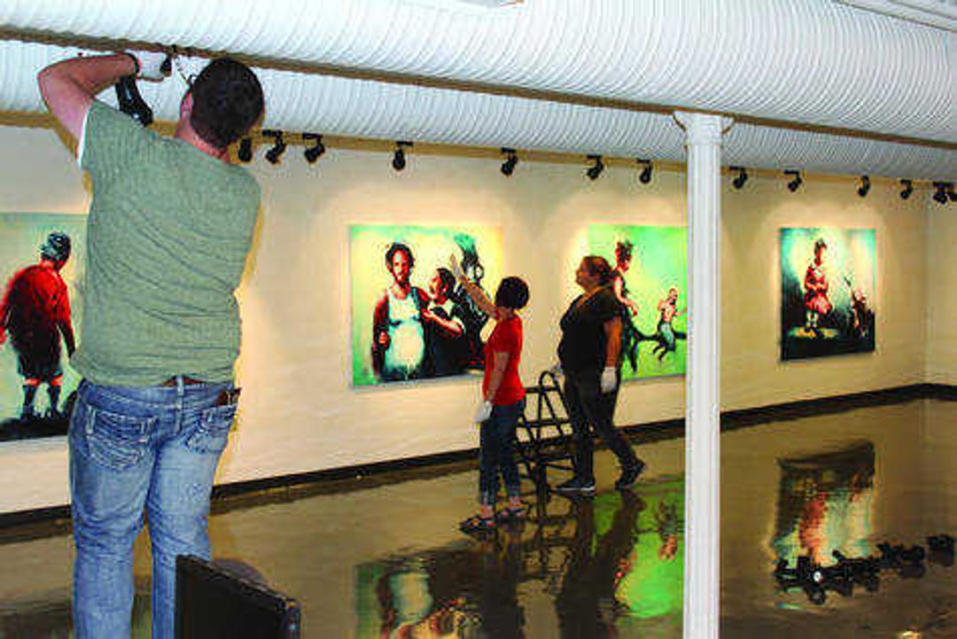 Gallery Coordinator Kristin Powers-Nowlin and students work together to hang Brent Webb's canvases in the River Campus Art Gallery on Sept. 5.