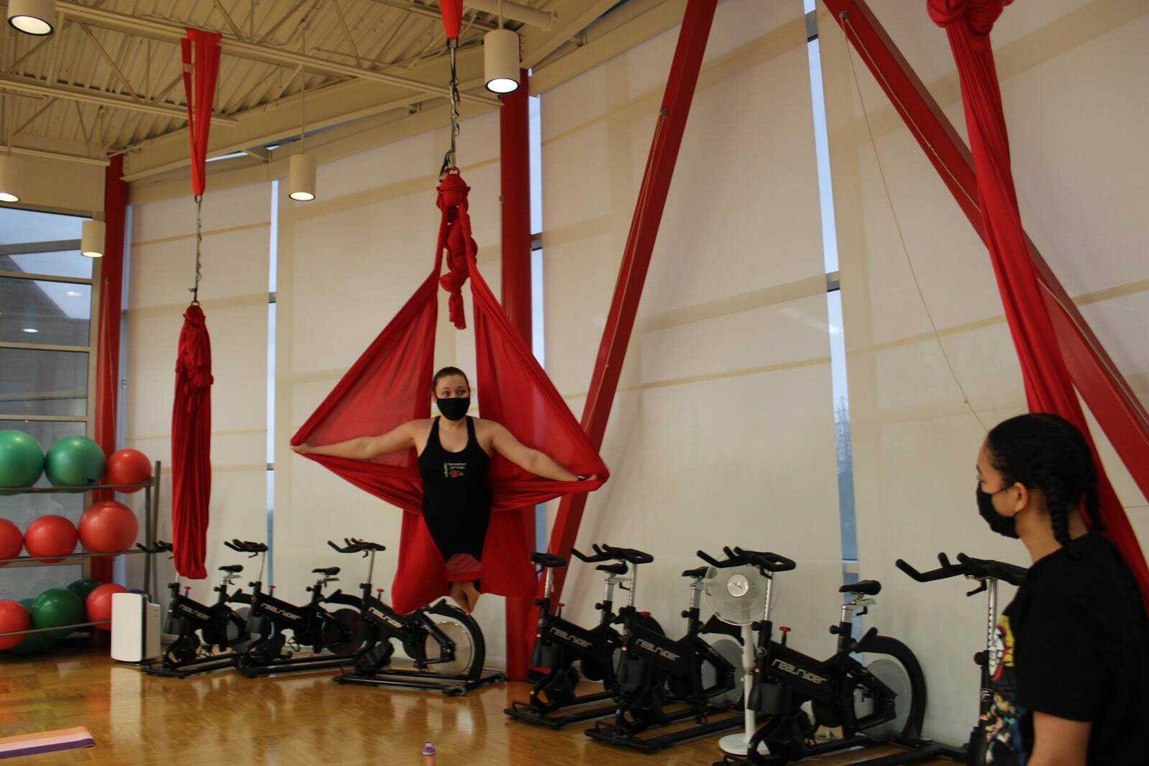 During the skills portion of the aerial yoga class, instructor Danielle Naeger demonstrates the “butterfly” pose as student Calantha Remy watches.