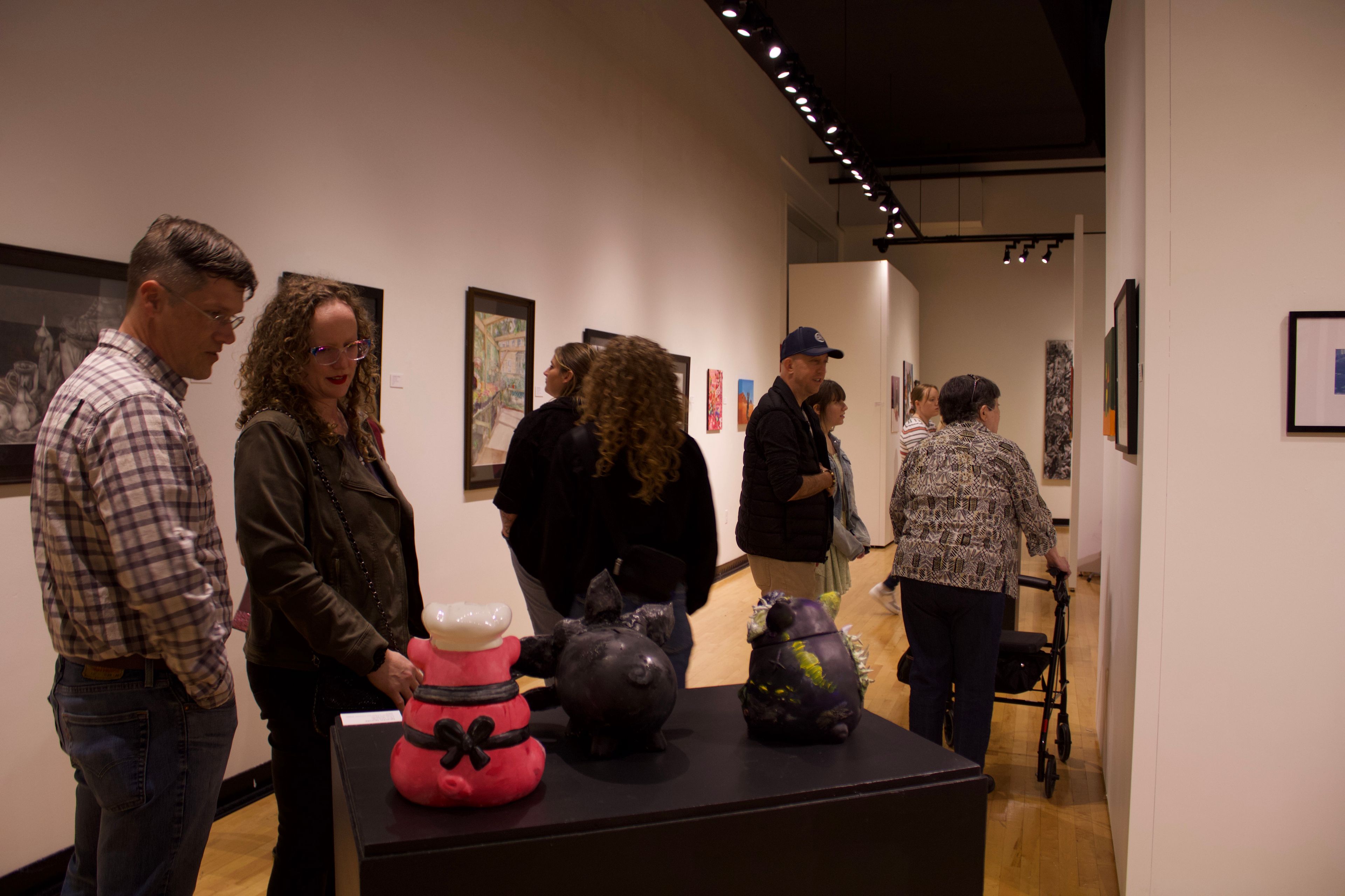 Guests admiring the art showcased at the Annual Juried Student Exhibition.