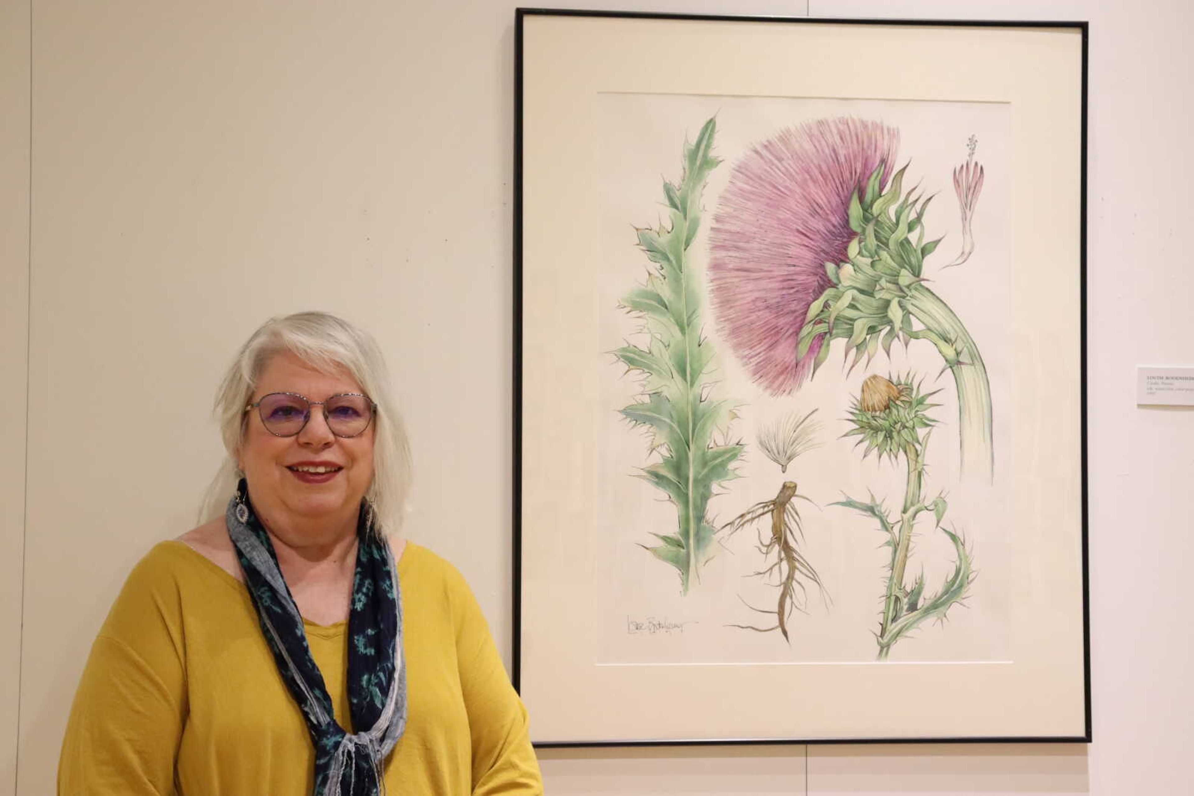 SEMO professor of Art & Design Louise Bodenheimer poses in front of one of her favorite art pieces, a pink thistle. The piece is featured in a collection of over 300 total artistic works in Bodenheimer's "Hybrid" gallery at the Crisp Museum.