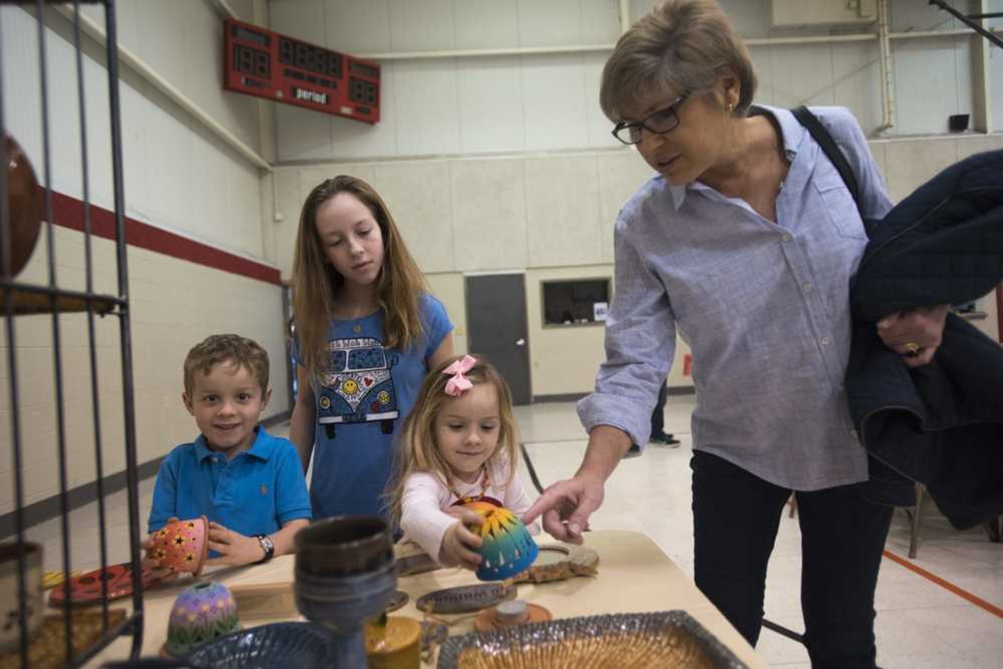 Barb Morgan looks at decorative bowls with the Brandhorst children, from left, Conrad, 6, Annabelle, 11, and Genevieve, 4, during the Empty Bowls Banquet on Sunday.