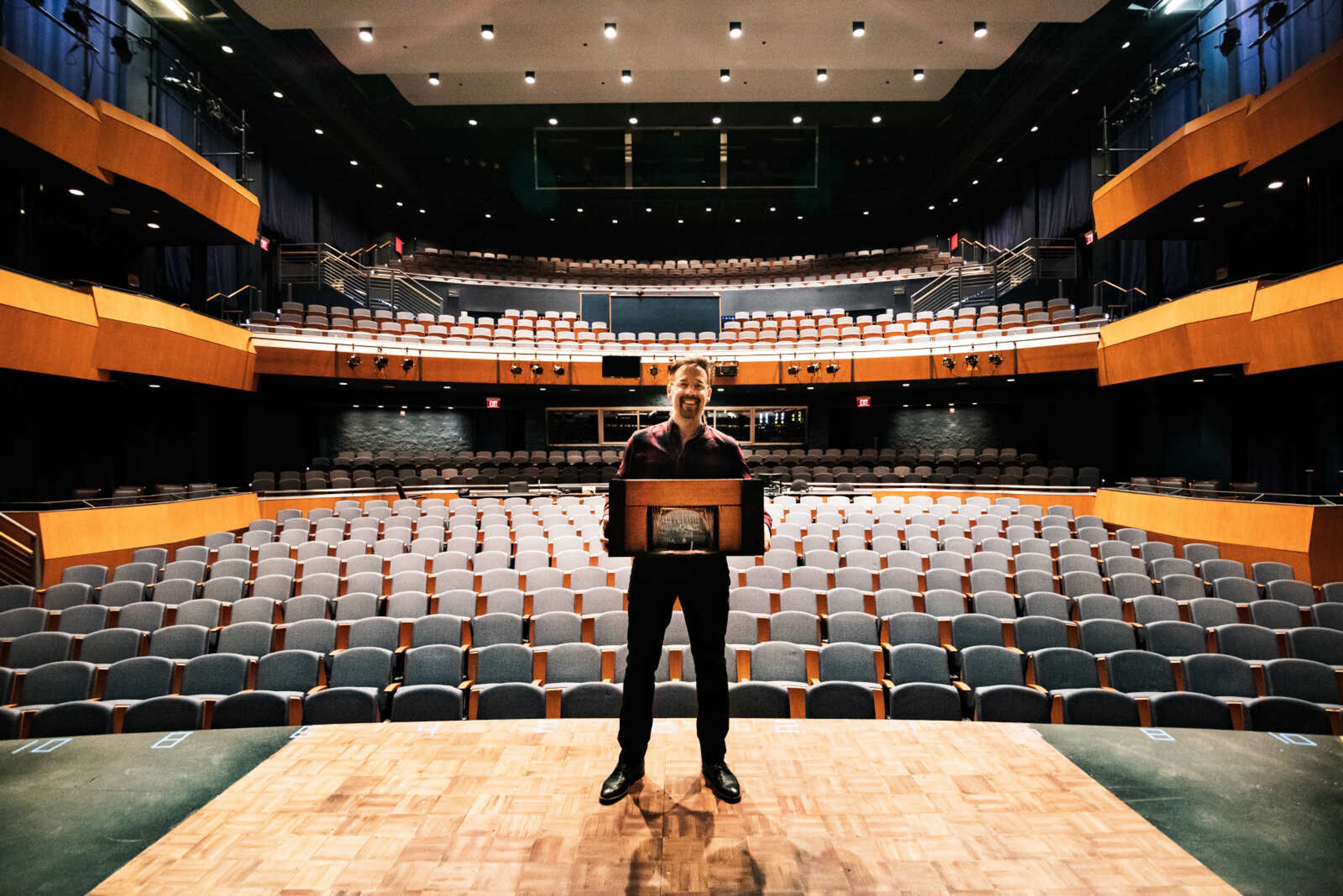 Matthew Buttrey holding a replica model of the 'Sister Act' stage set in Shuck Recital Hall.
