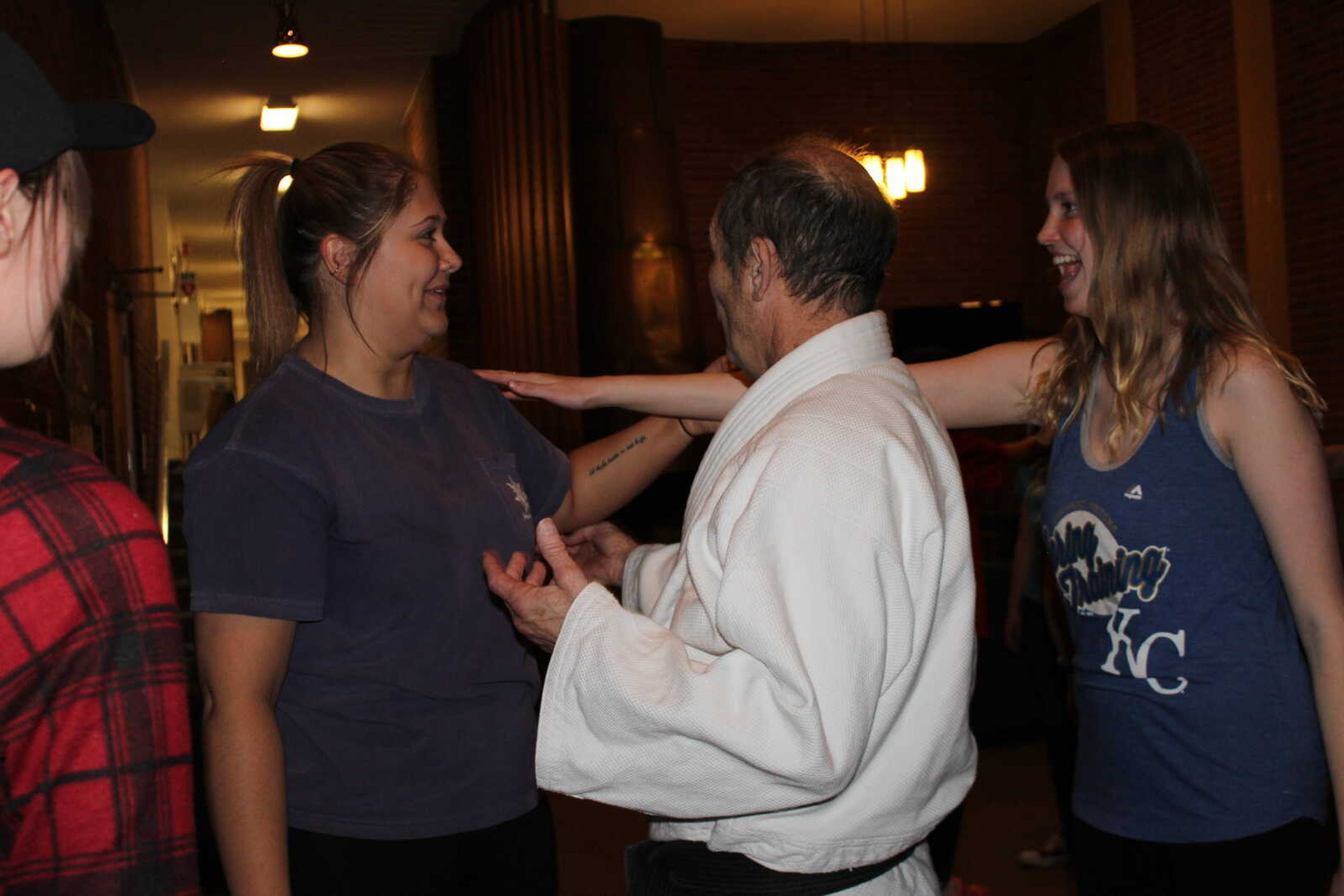 Self defense instructor Doug Johnson helps RAs Katy Armstrong and Alaina Mikkelsen perfect a technique they were just taught.