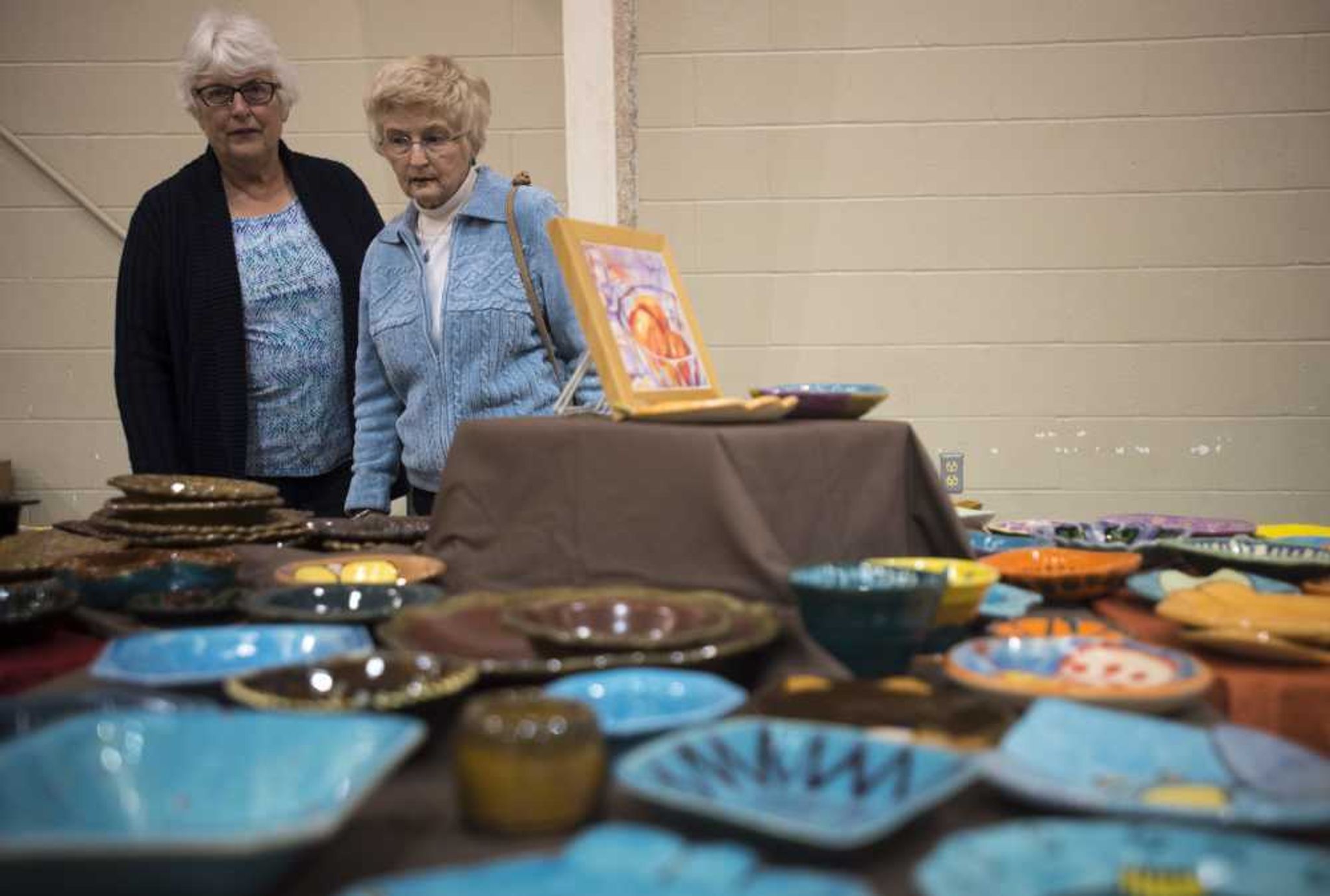 Nancy Glosemeyer, left, and Marilyn Harrison look at decorative bowls during the Empty Bowls Banquet on Sunday.