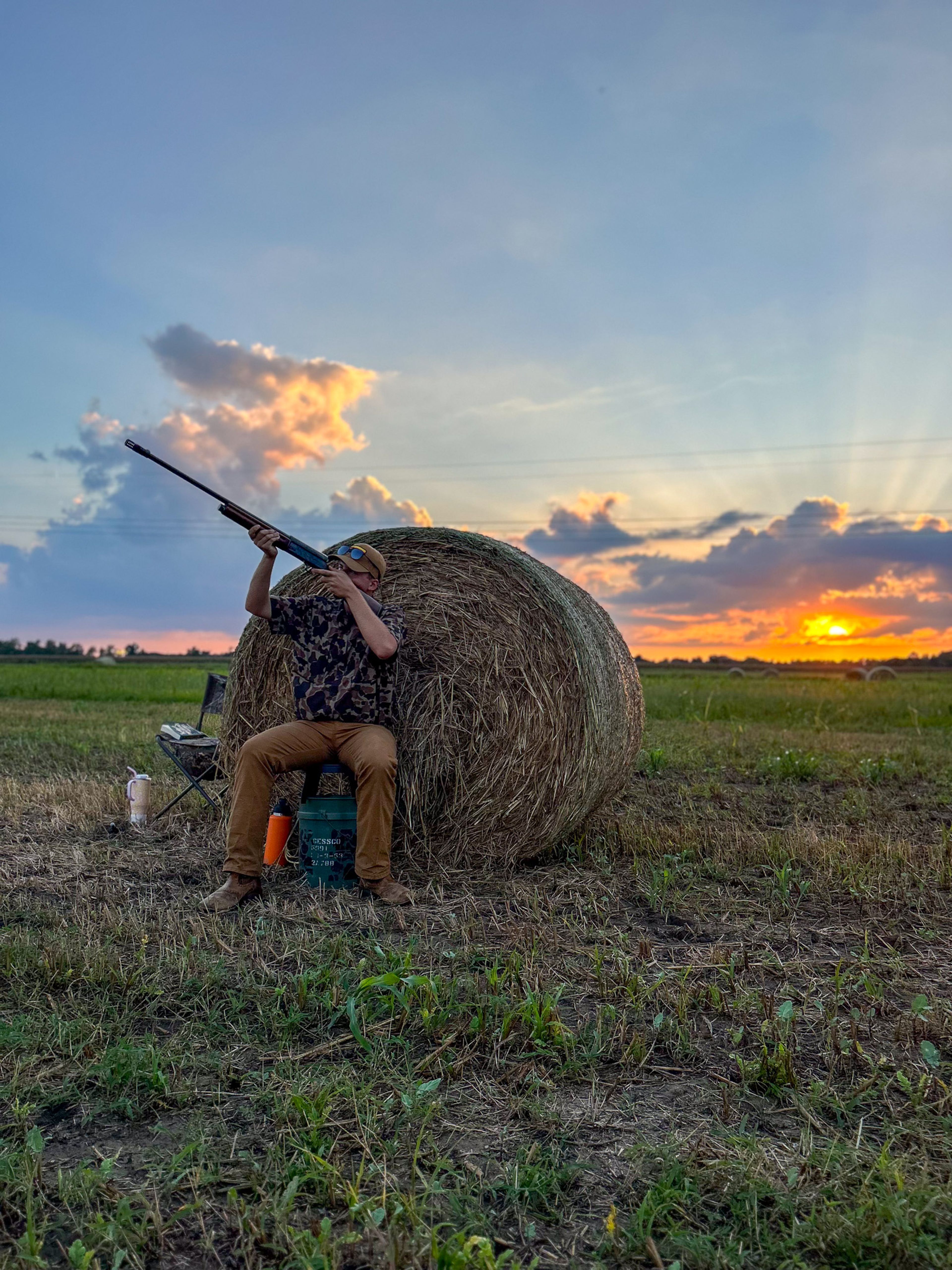 Bryson Klunk shoulders his gun as doves fly by at sunset.