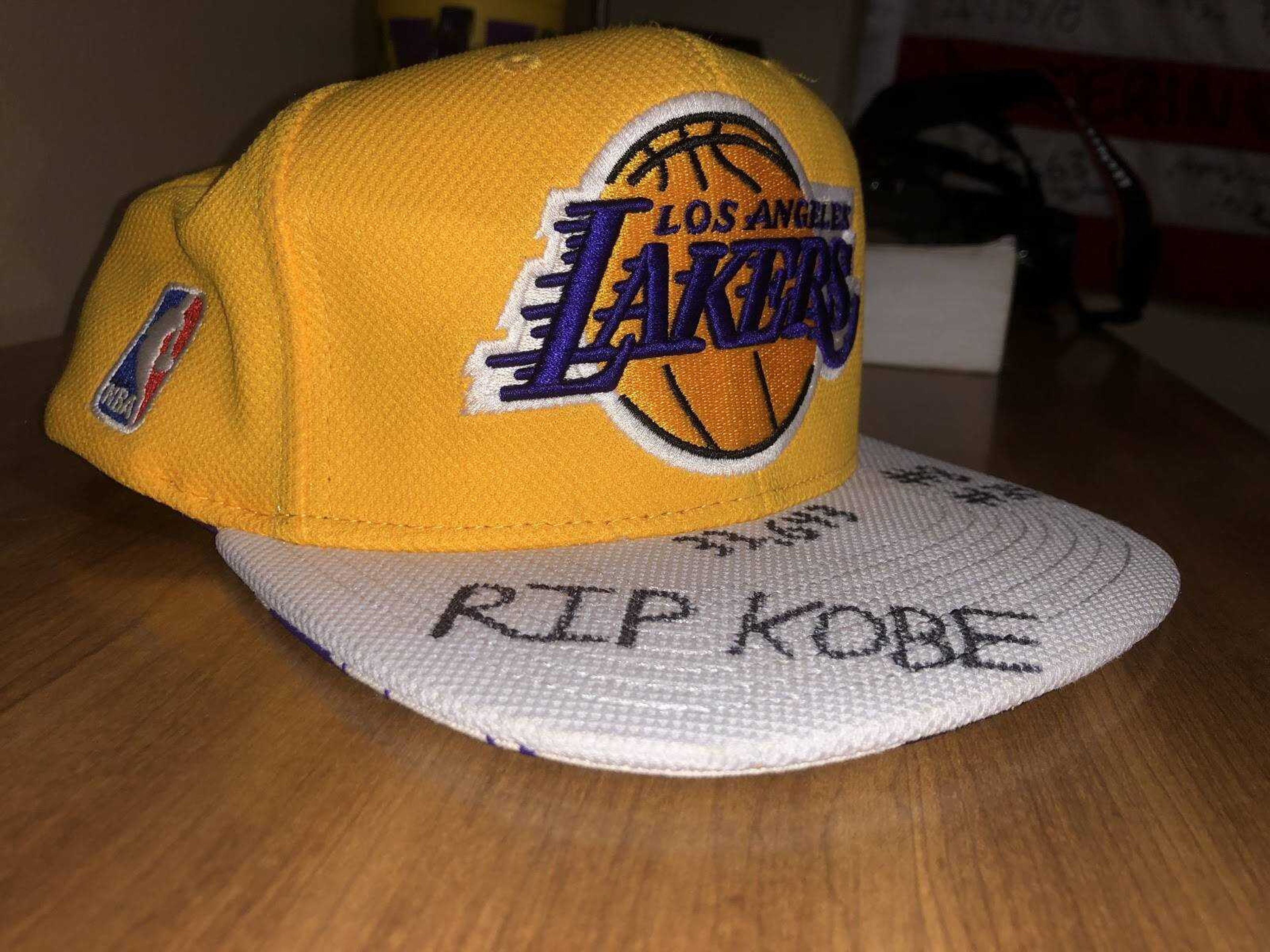 A Los Angeles Lakers hat with “RIP KOBE” written in large print on the top of the bill. Both “#8” and “#24” are written on the right side of the hat for the two numbers Kobe Bryant wore during his 20 year career. The number “33,463” is written at the center of the hat for the number of points Bryant scored in his career, fourth-most in the history of the National Basketball Association.