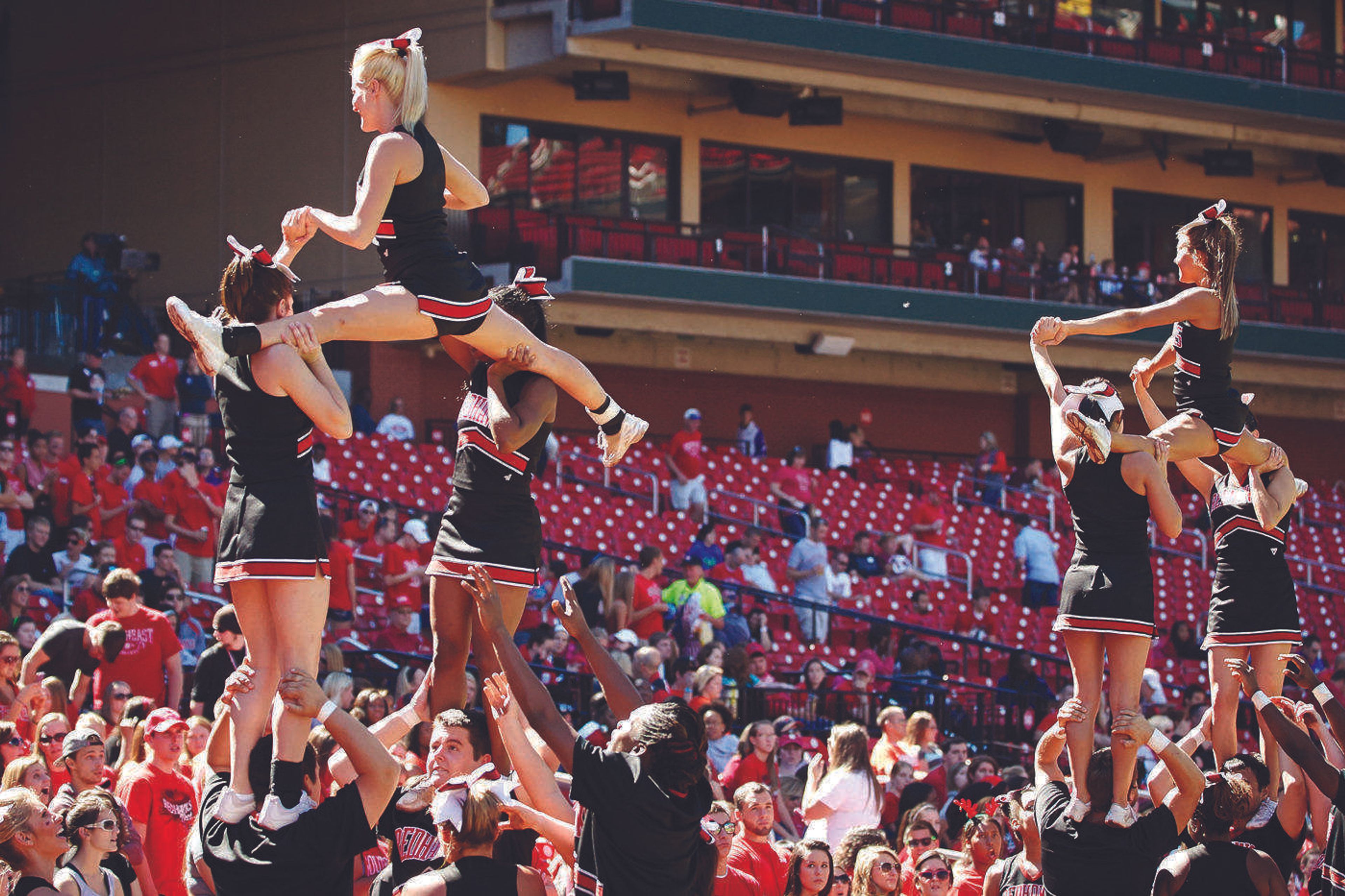 Cheerleaders stunt with alumni on homecoming
