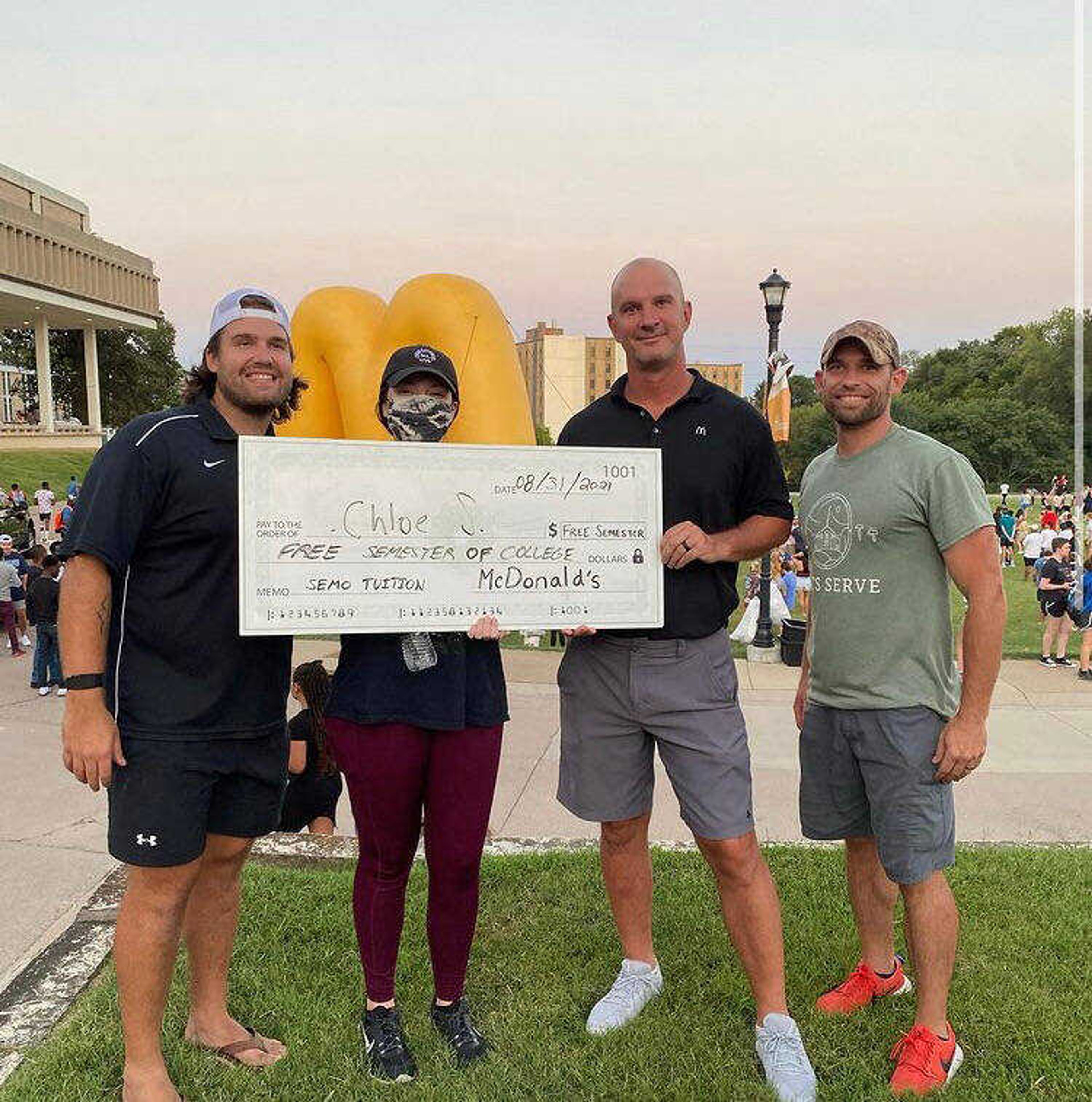Student and organizers pose with free semester of college check at "Big Bucks & BBQ" event. From left to right: Joey Babich, Chloe Sutherland, John Haggerty, Reece Hammond. Photo by Jeff Brune.