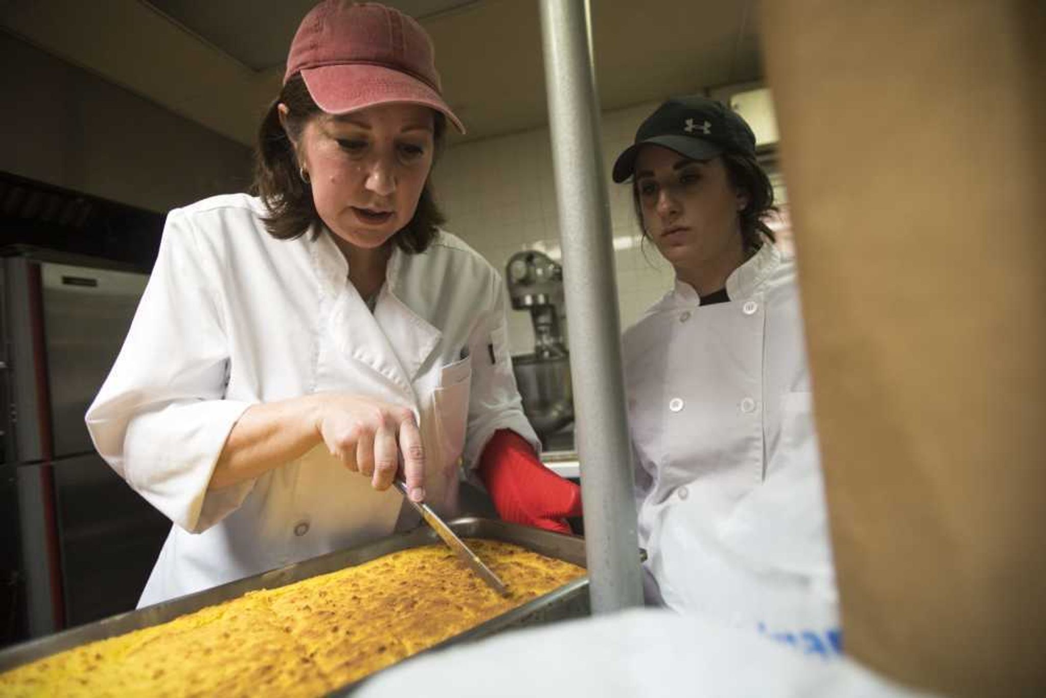 Sarah Bower, right, watches as Paulla White cuts cornbread before the Empty Bowls Banquet on Sunday.