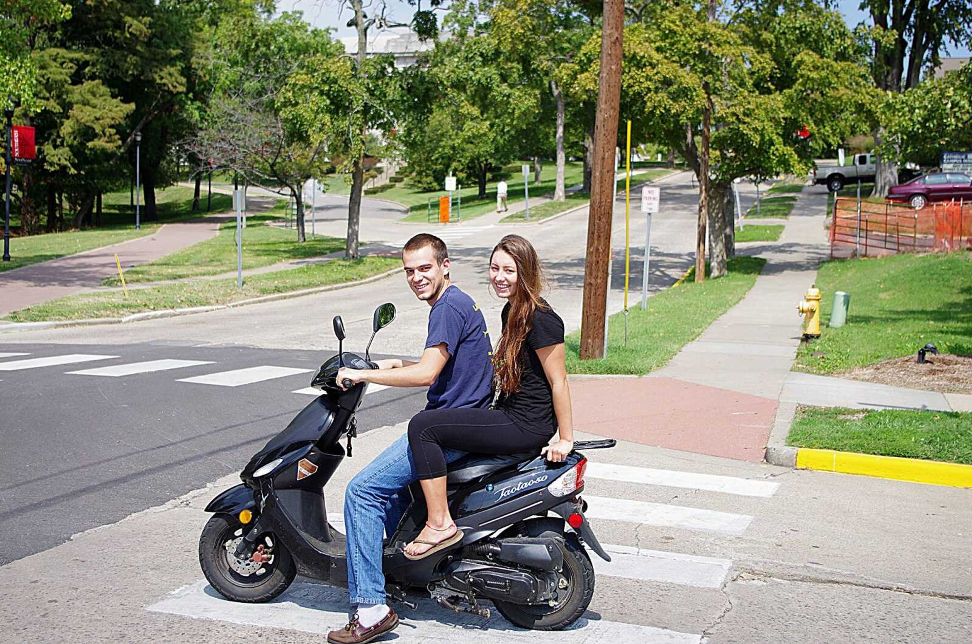 Two Southeast students ride on a scooter through the intersection of Normal Avenue and Pacific Street. Photo by Nathan Hamilton