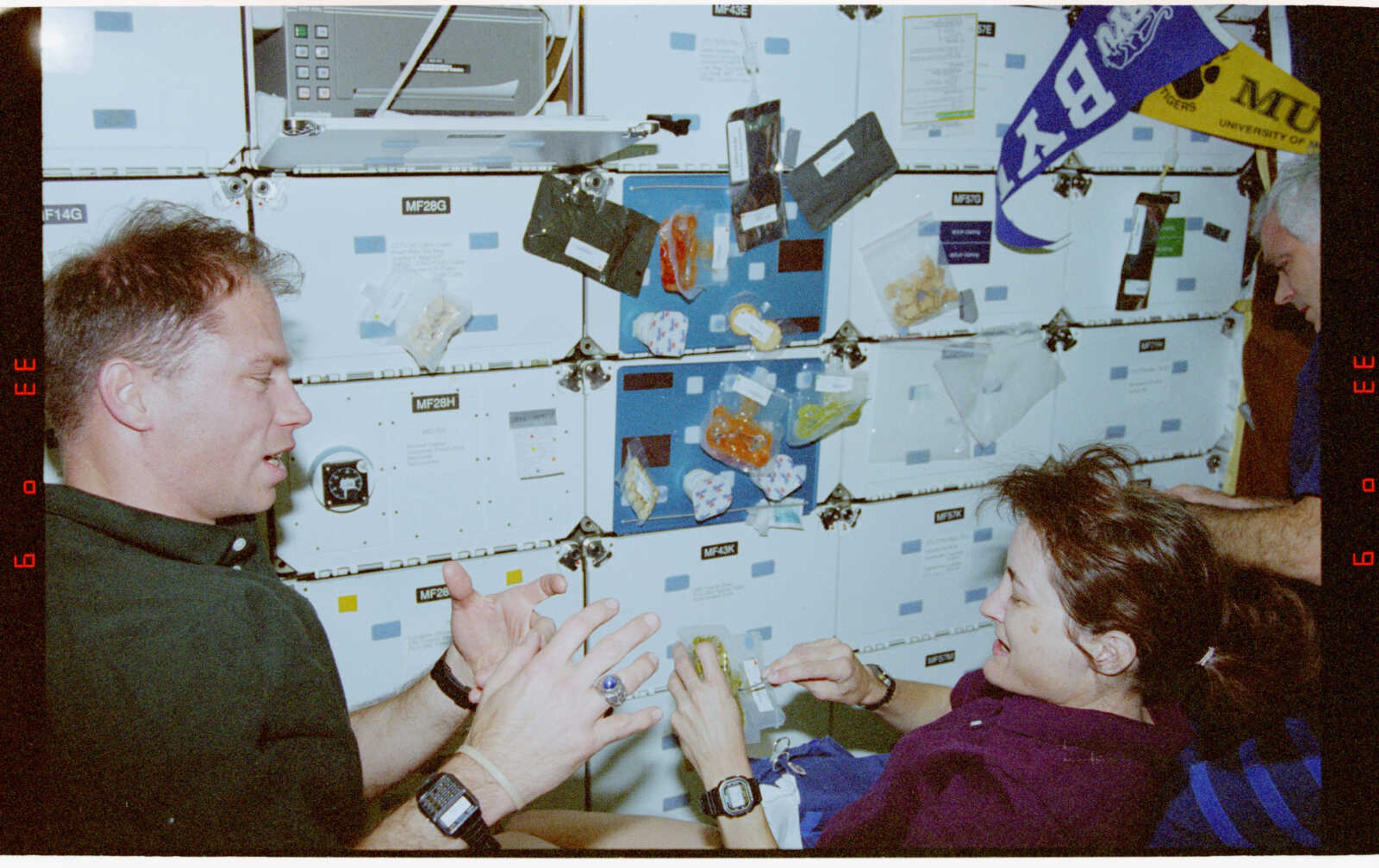 Pilot Rick Searfoss talks with Mission Specialist Linda Godwin as she eats in-orbit.
