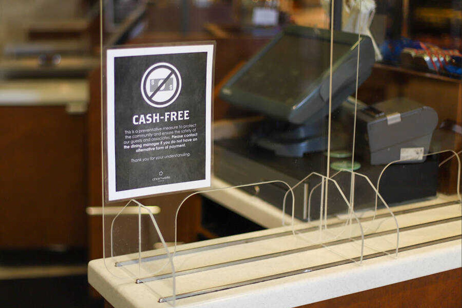 A flyer reminding diners to pay for meals by cashless payment sits on the divider between the cashiers and diners. Chartwells made the decision to move to cashless payments to cut down on the germs that can be spread through paper money, diners can use their student ID's or debit/credit cards to pay. 