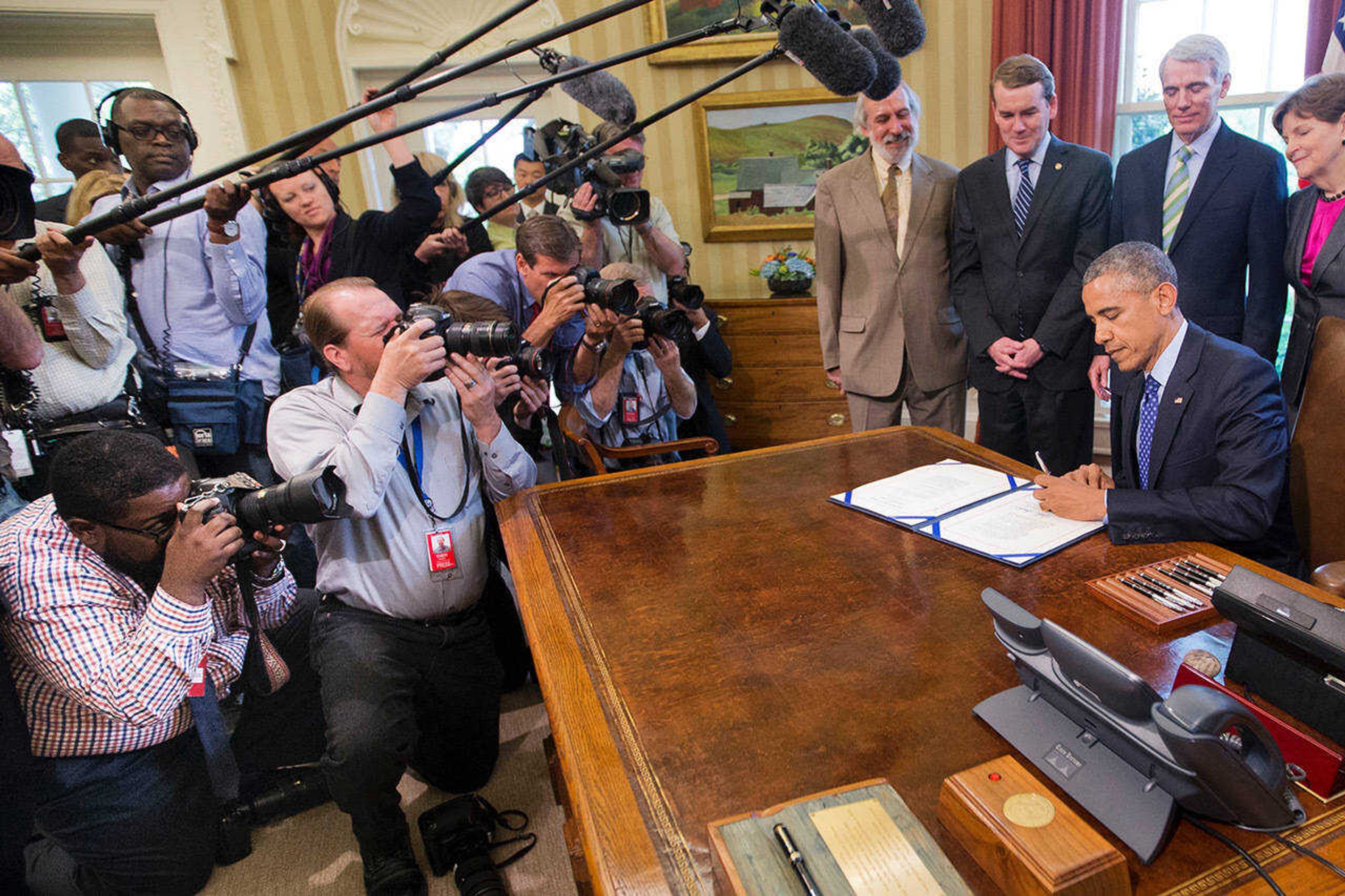 Kneeling left, Michael Thomas photographs President Barack Obama as he signs bill S. 535 Energy Efficiency Improvement Act of 2015 in the Oval Office of the White House in Washington, Thursday, April 30, 2015.