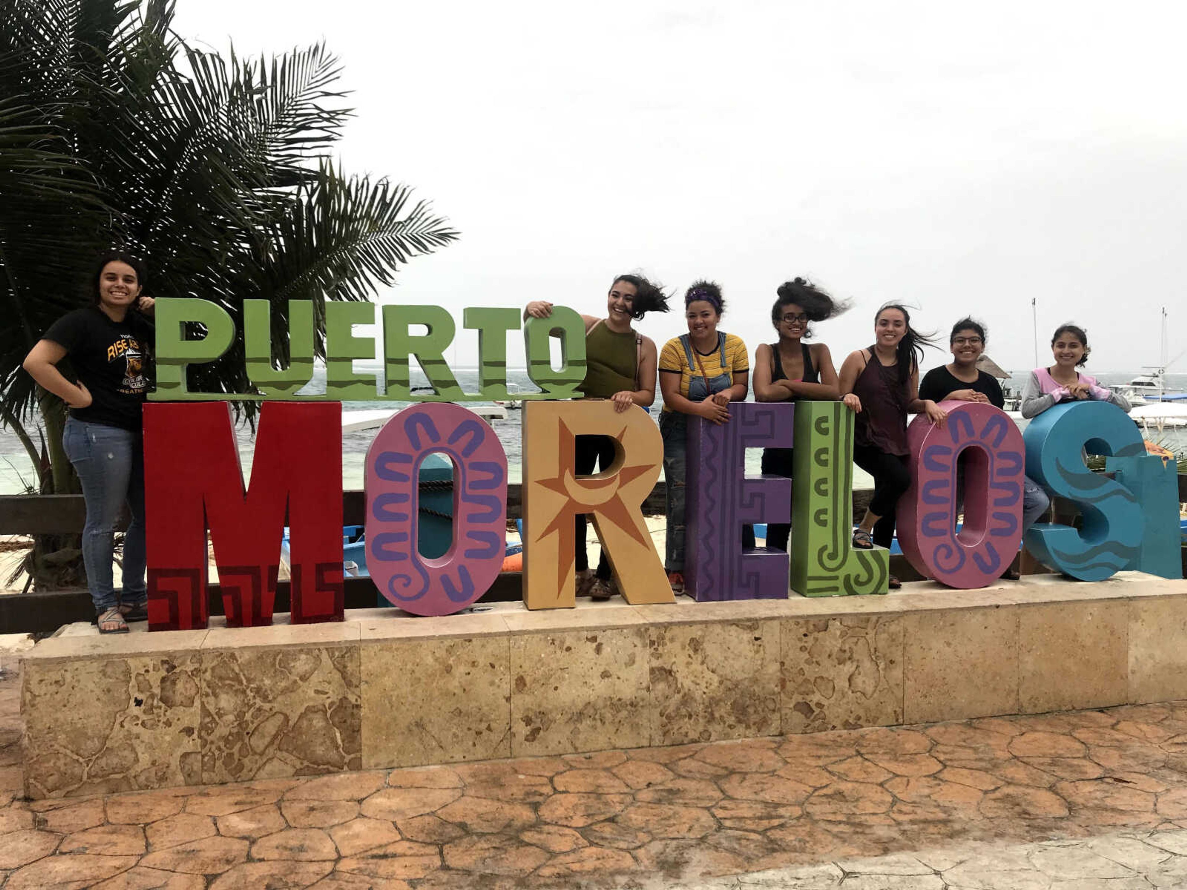 A group photo with a Puerto Morelos sign with Gamboa and other interns.
