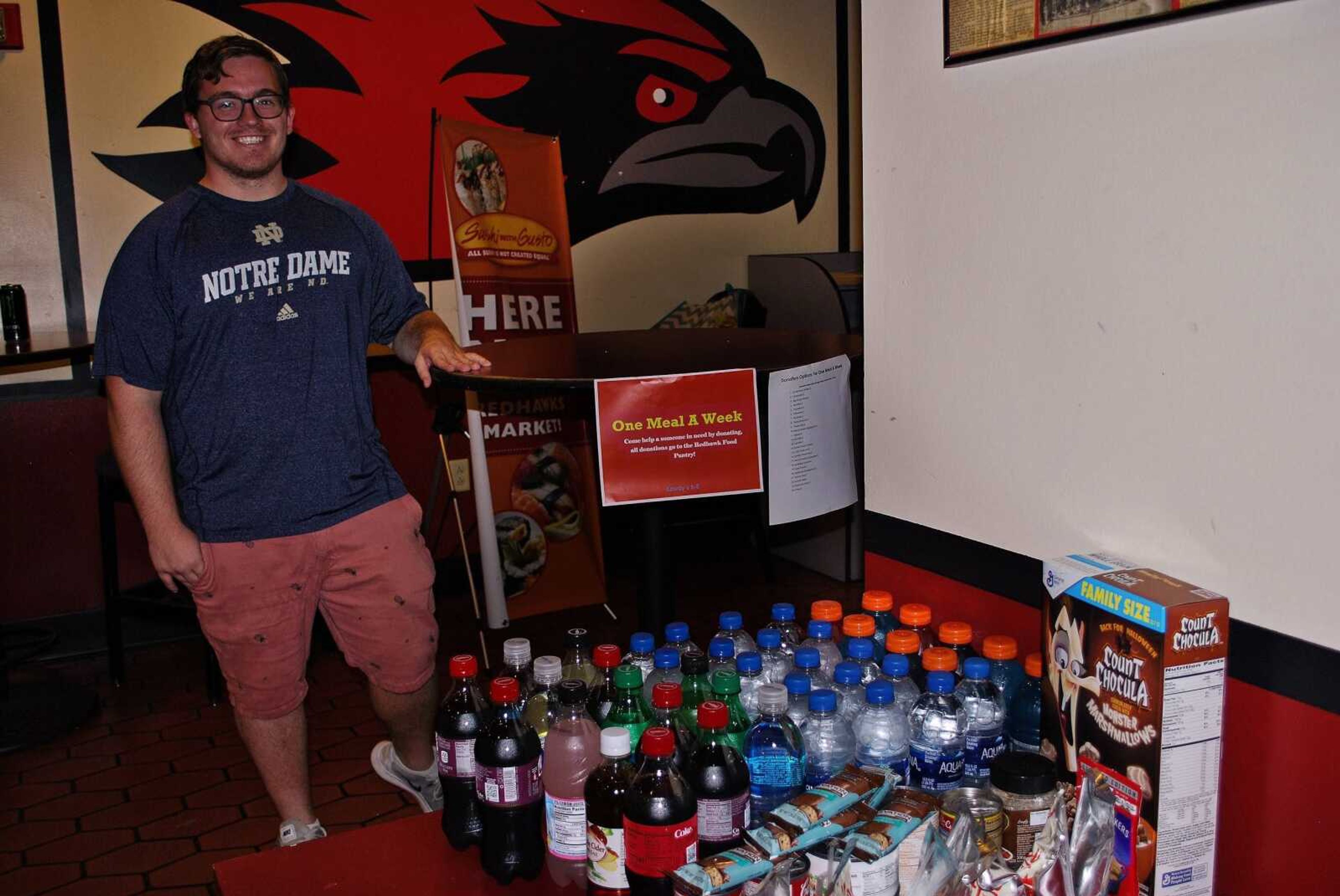 Gabrione Kent poses near the food donated to the pantry in Rowdy’s.