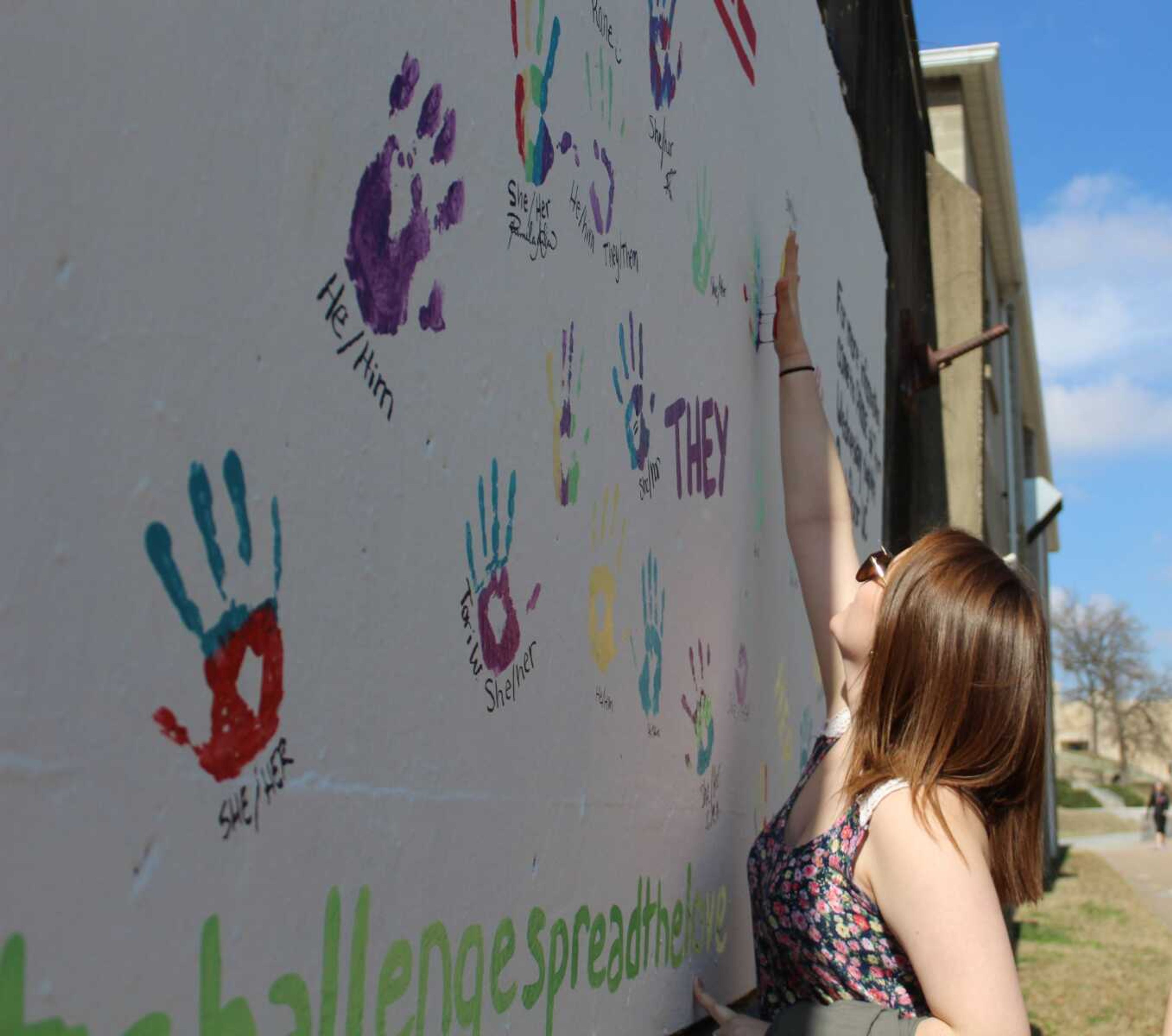 Freshman Ashelee Chaney puts her handprint on the PRIDE graffiti wall.