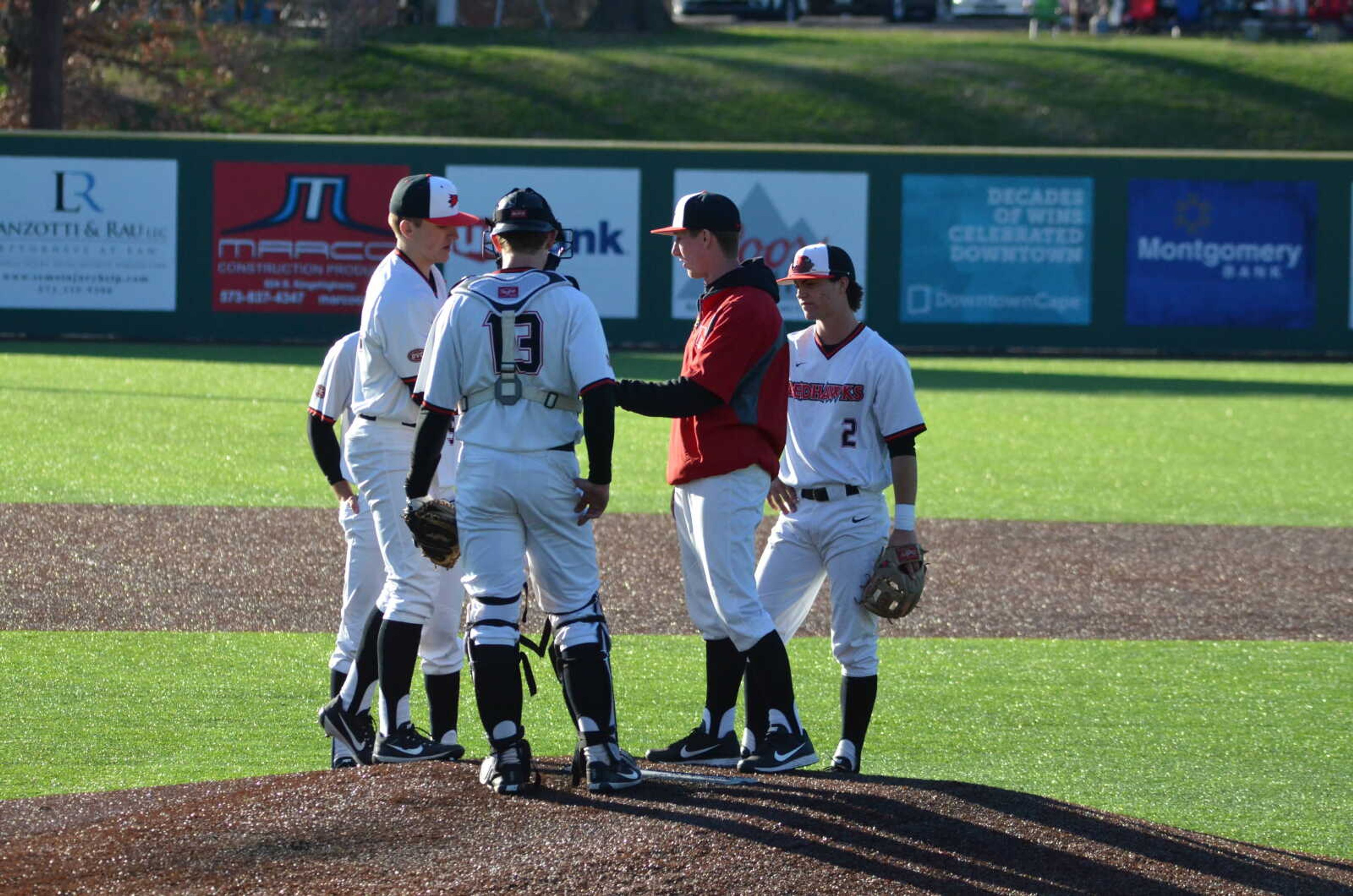 Members of the Southeast baseball team meet on the mound during a pitching change during the game.