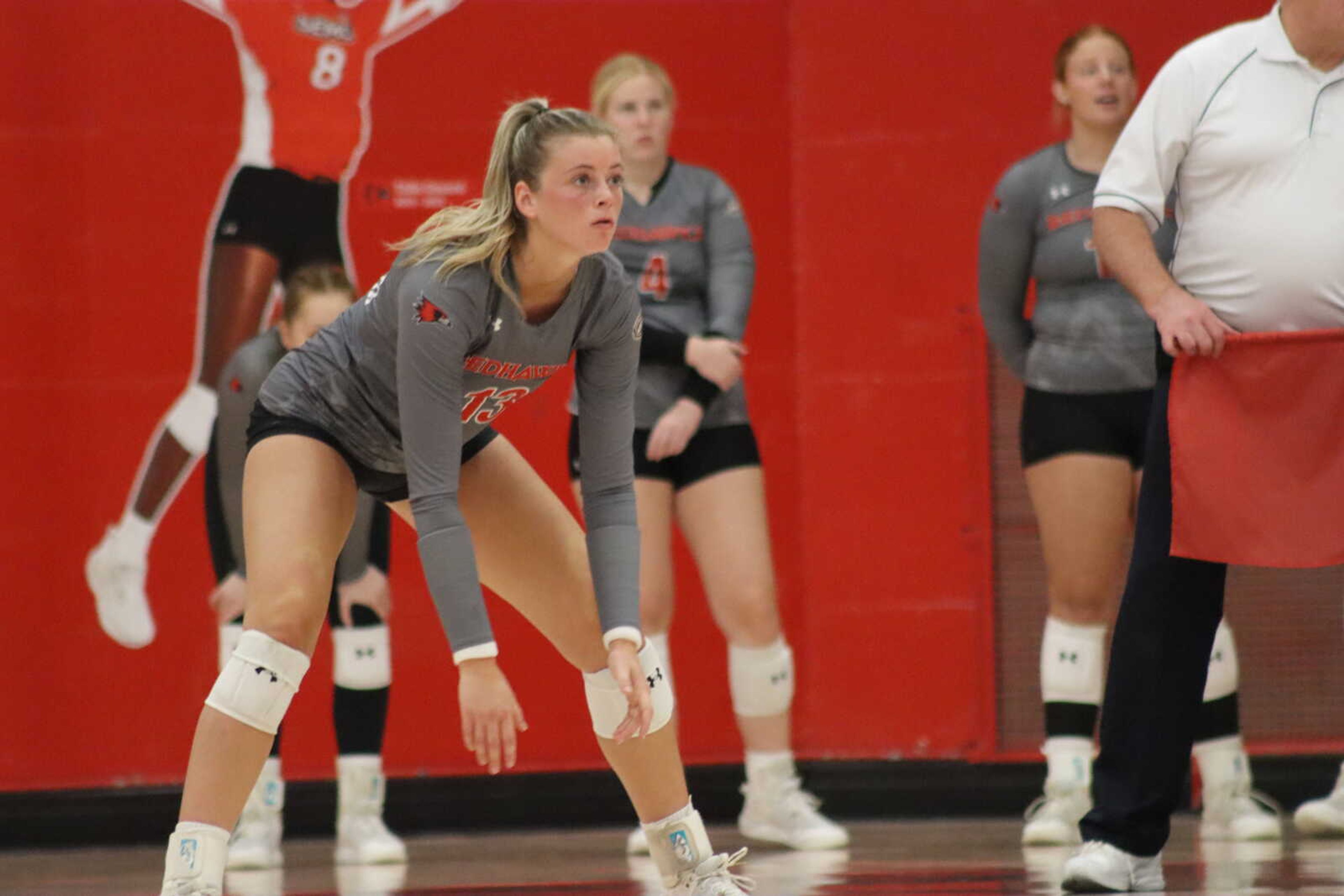 Senior outside hitter Kayla Closset (13) locks in as she prepares for a play, while teammates watch on in the background.
