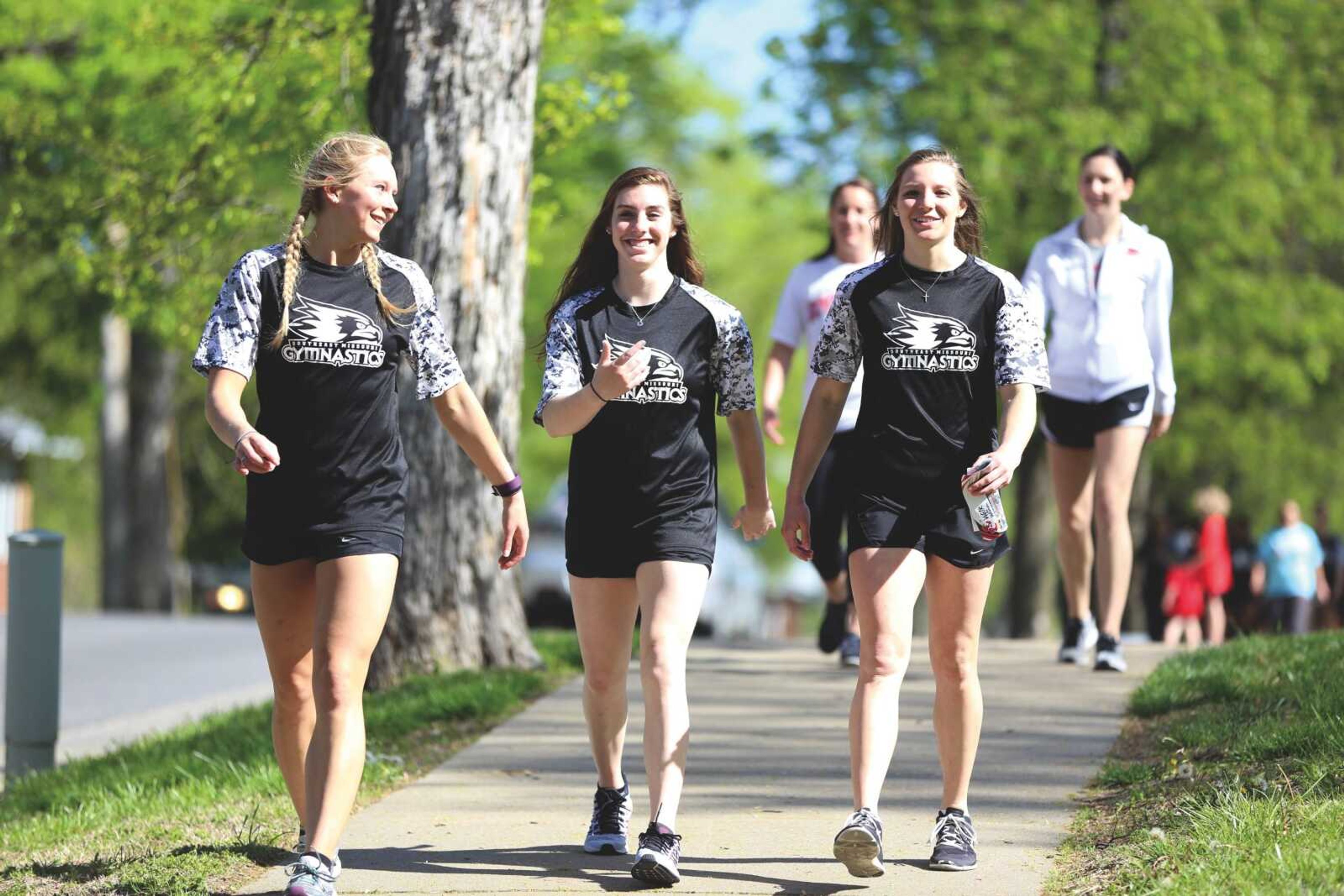 Gymnasts Taylor Penzien (left), McKenna Stanley and Ashley Thomas lead the Walk for Women back to Houck Field House on Saturday.