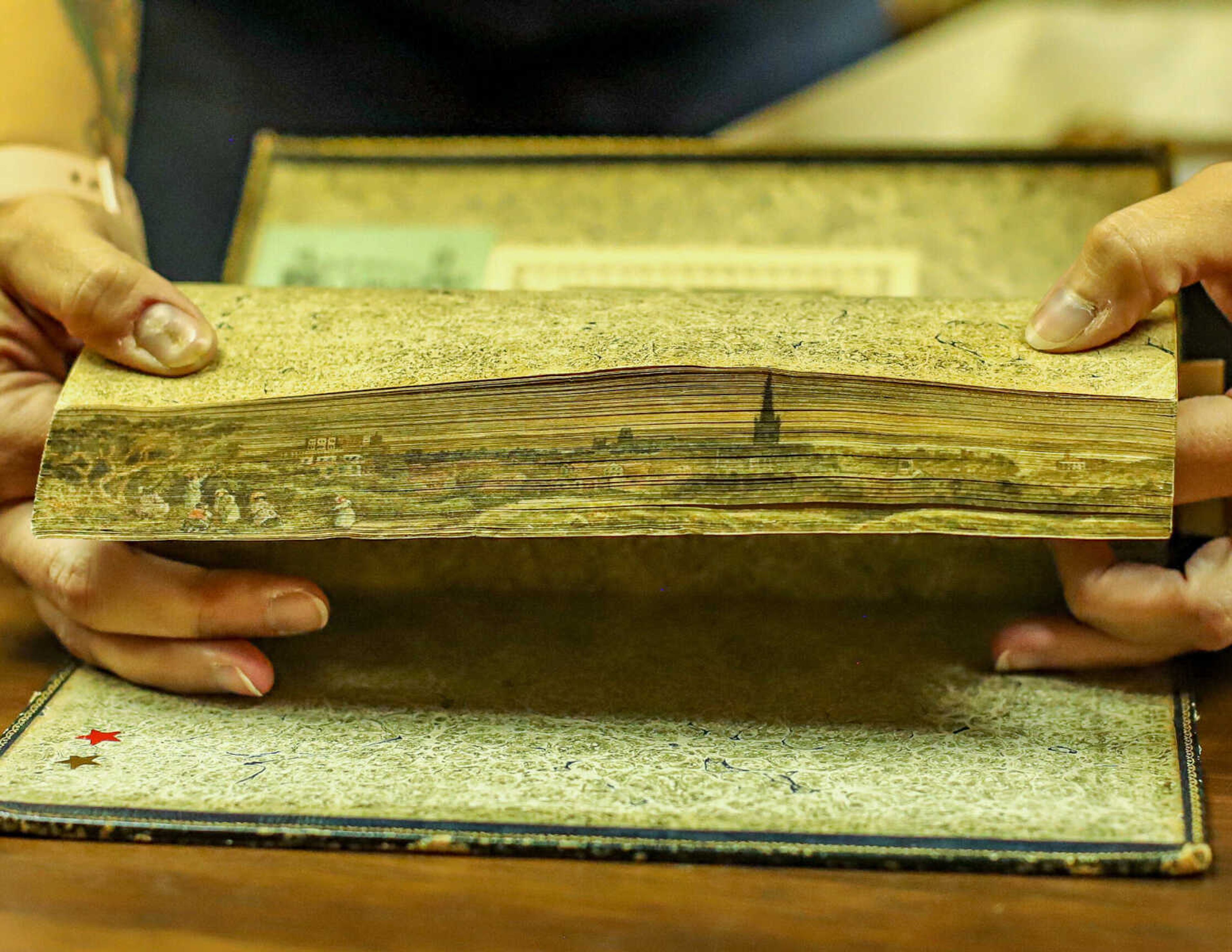 A text is fanned to display fore-edge painting, which is common with older books.