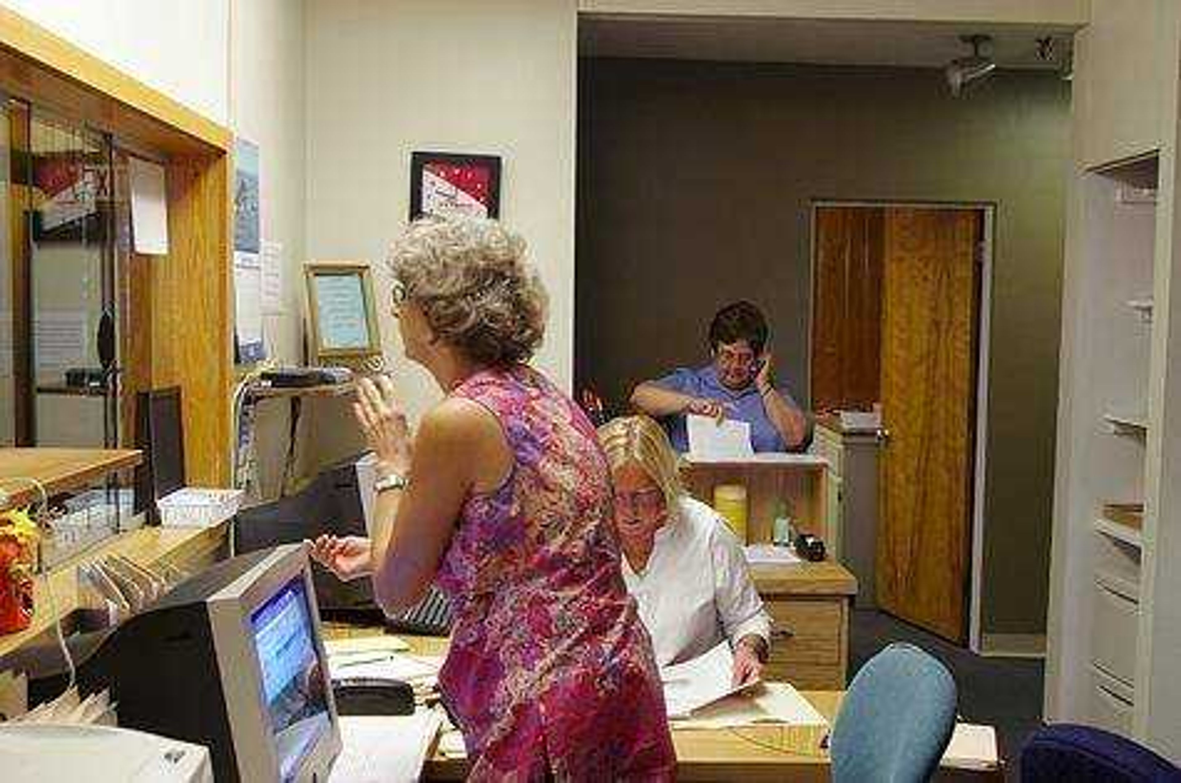 Andrea Sachse, Nancy Buchanan and Rhonda Sievers, the front desk staff, fill out paperwork. The clinic serves uninsured people. Photo by Nathan Hamilton