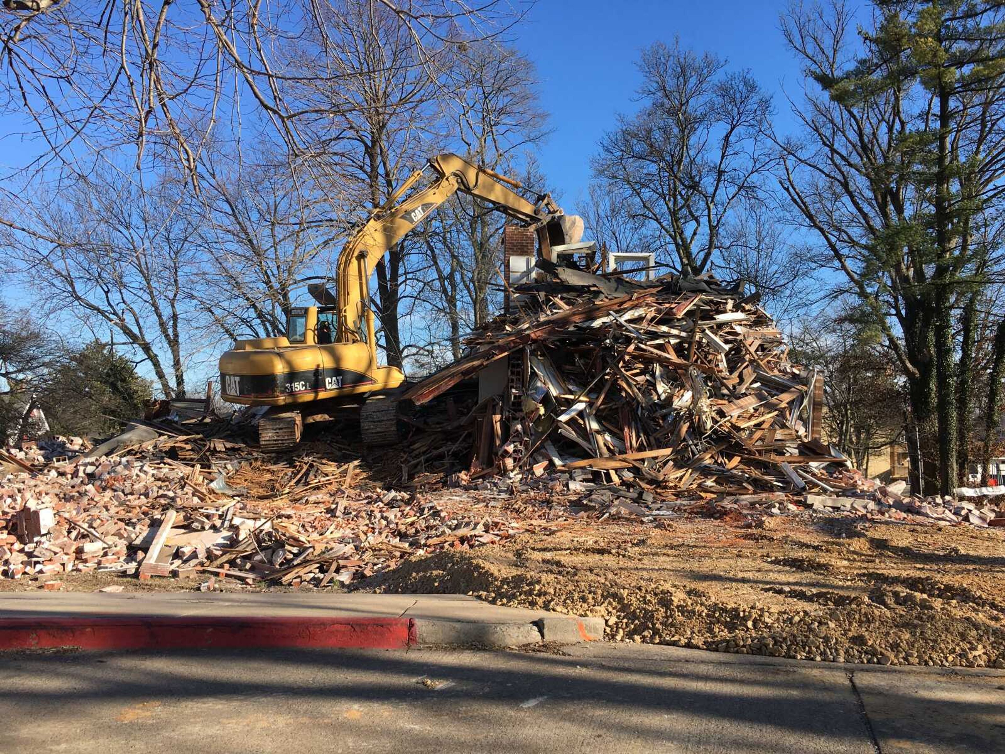 An excavator strikes the remaining structure of the former International Center at 939 College Hill Place on Jan. 7.