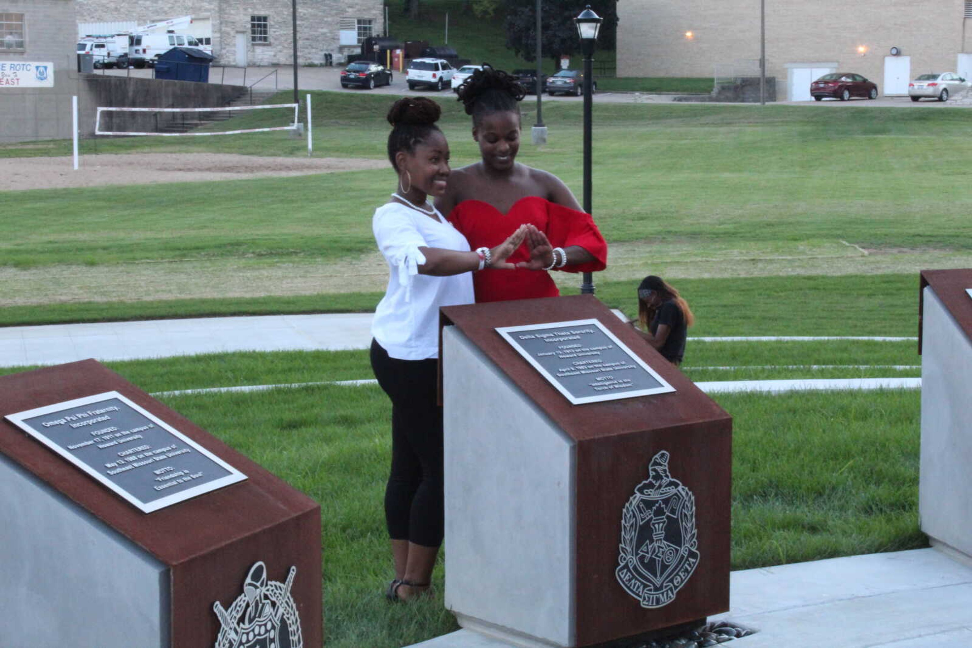 Jaleea Hudson-Wilson, left, and Andrea Cox, right, pose with the plaque honoring their organization Delta Sigma Theta, at the opening ceremony for the NPHC Plaza Aug. 16.